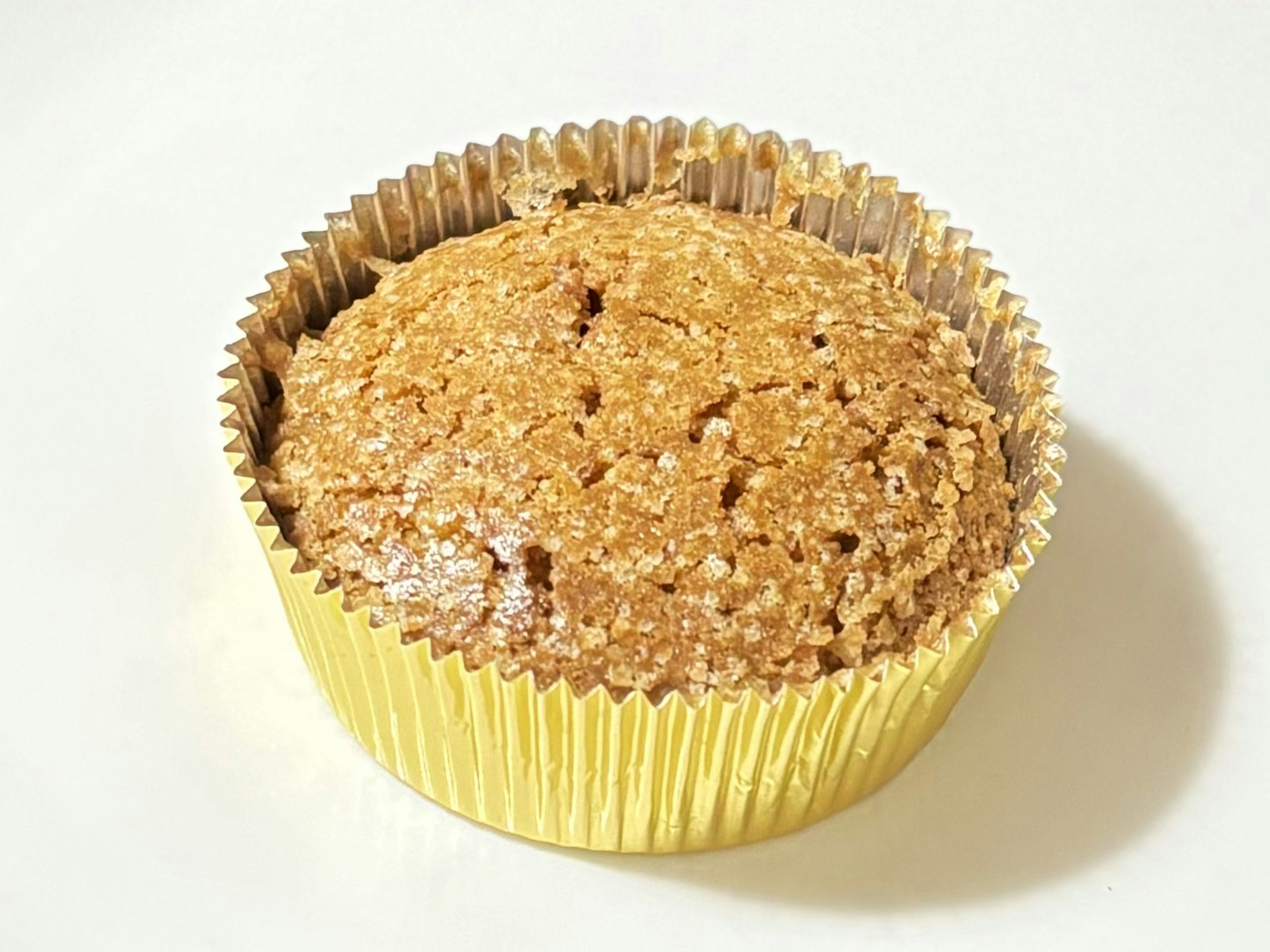 A muffin in a gold cupcake liner with a textured top