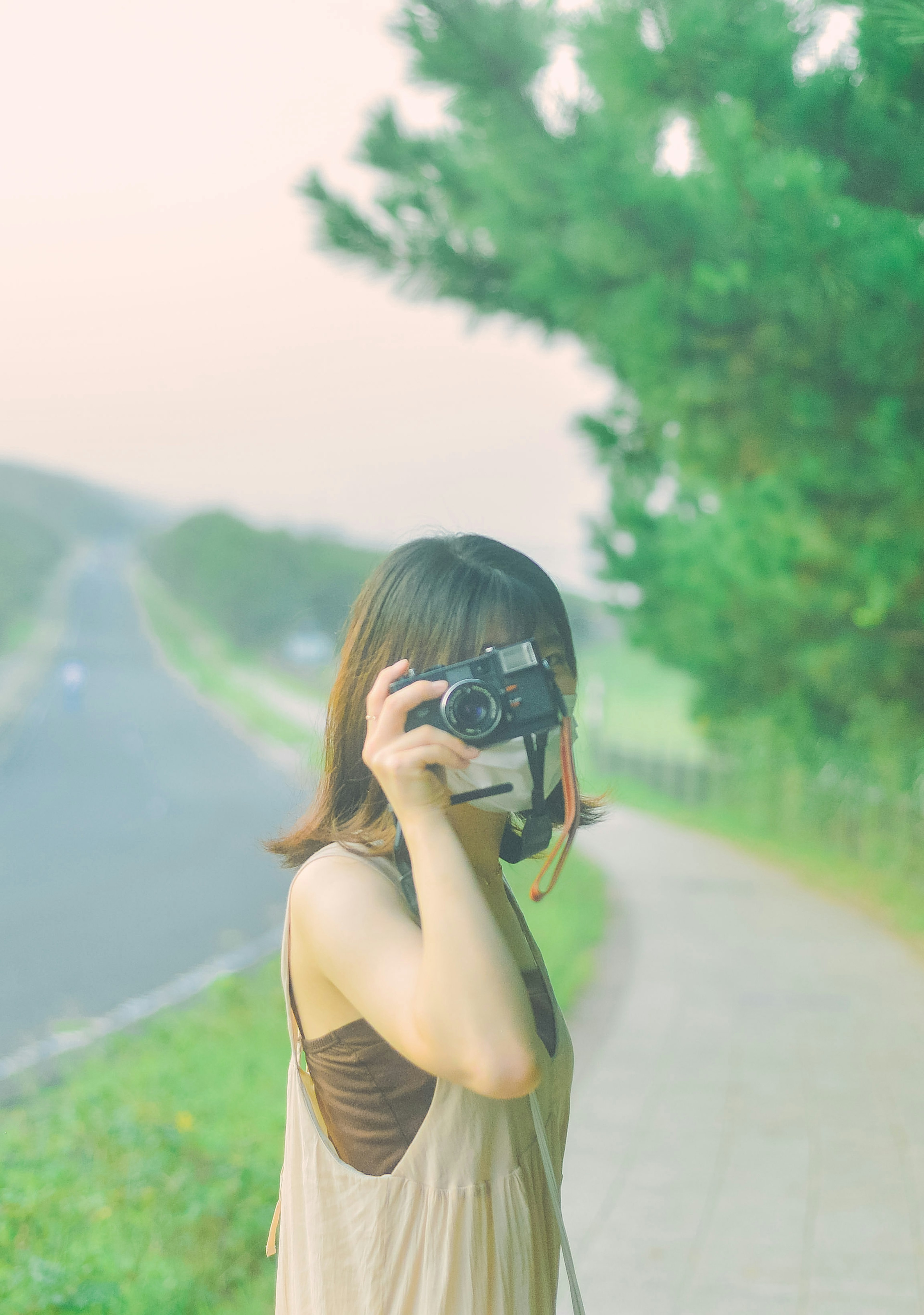 A woman holding a camera standing beside a road