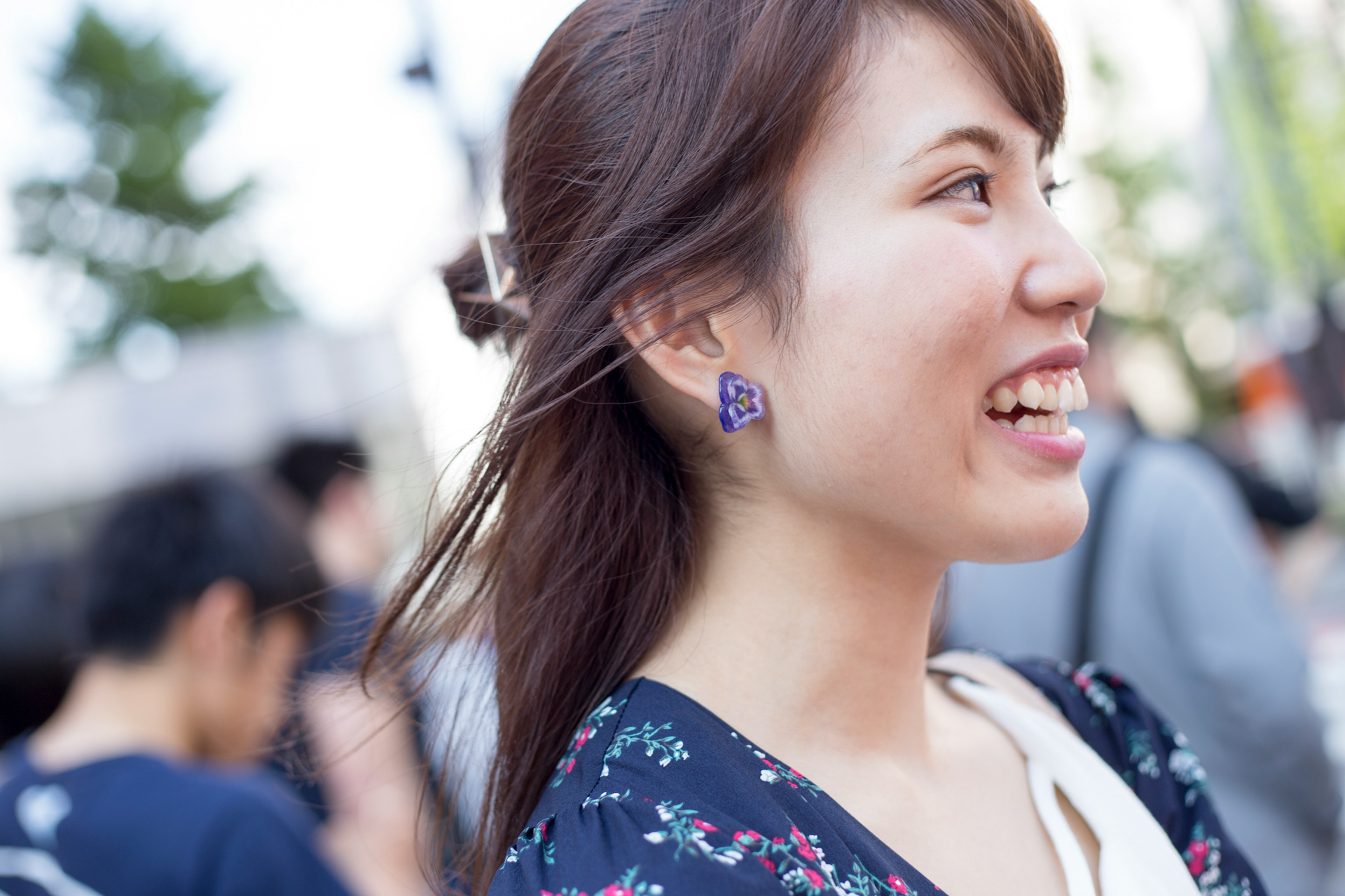 A woman smiling while looking sideways with people in the background