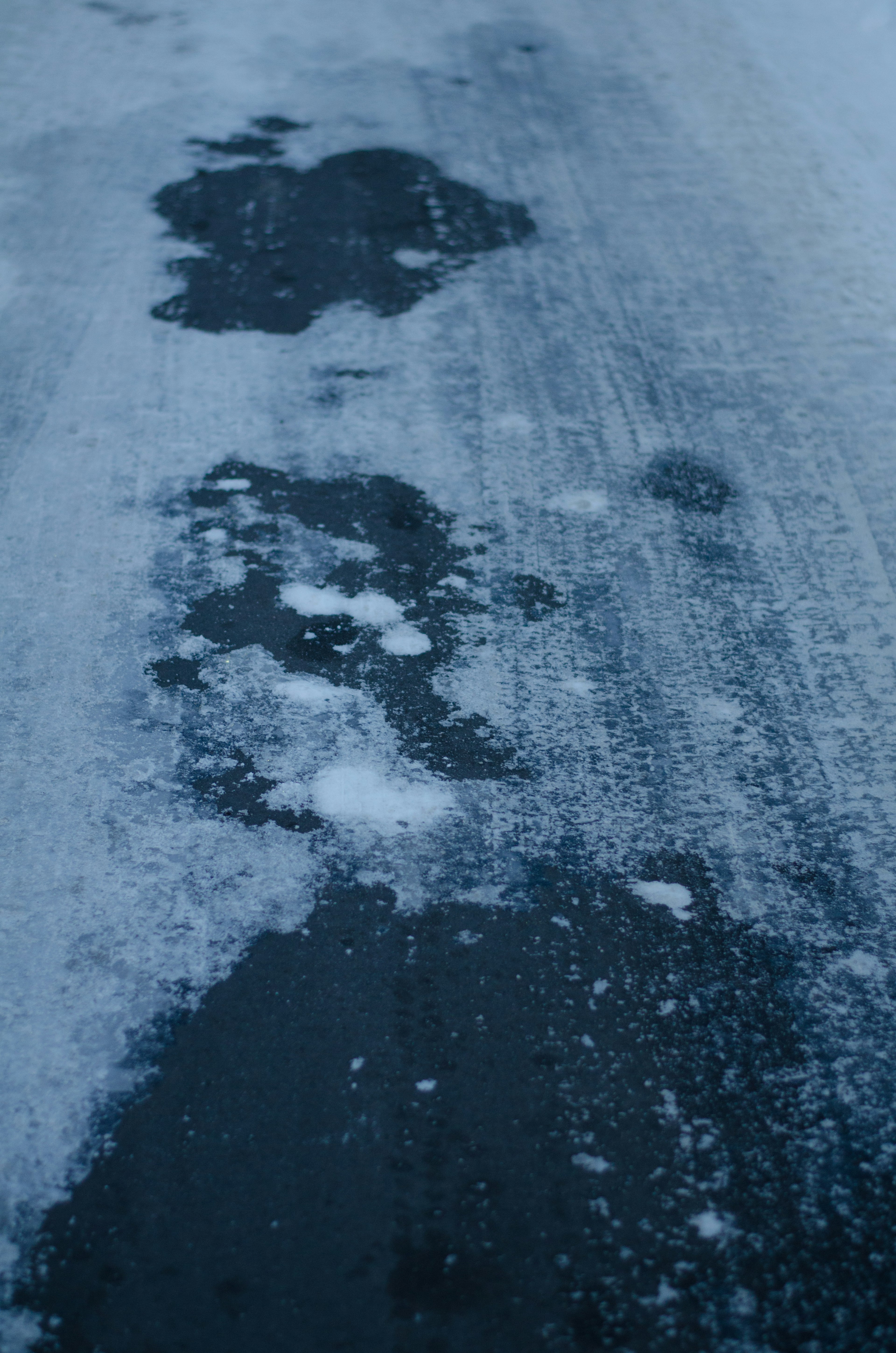 Immagine di una superficie stradale con macchie di ghiaccio nero e neve