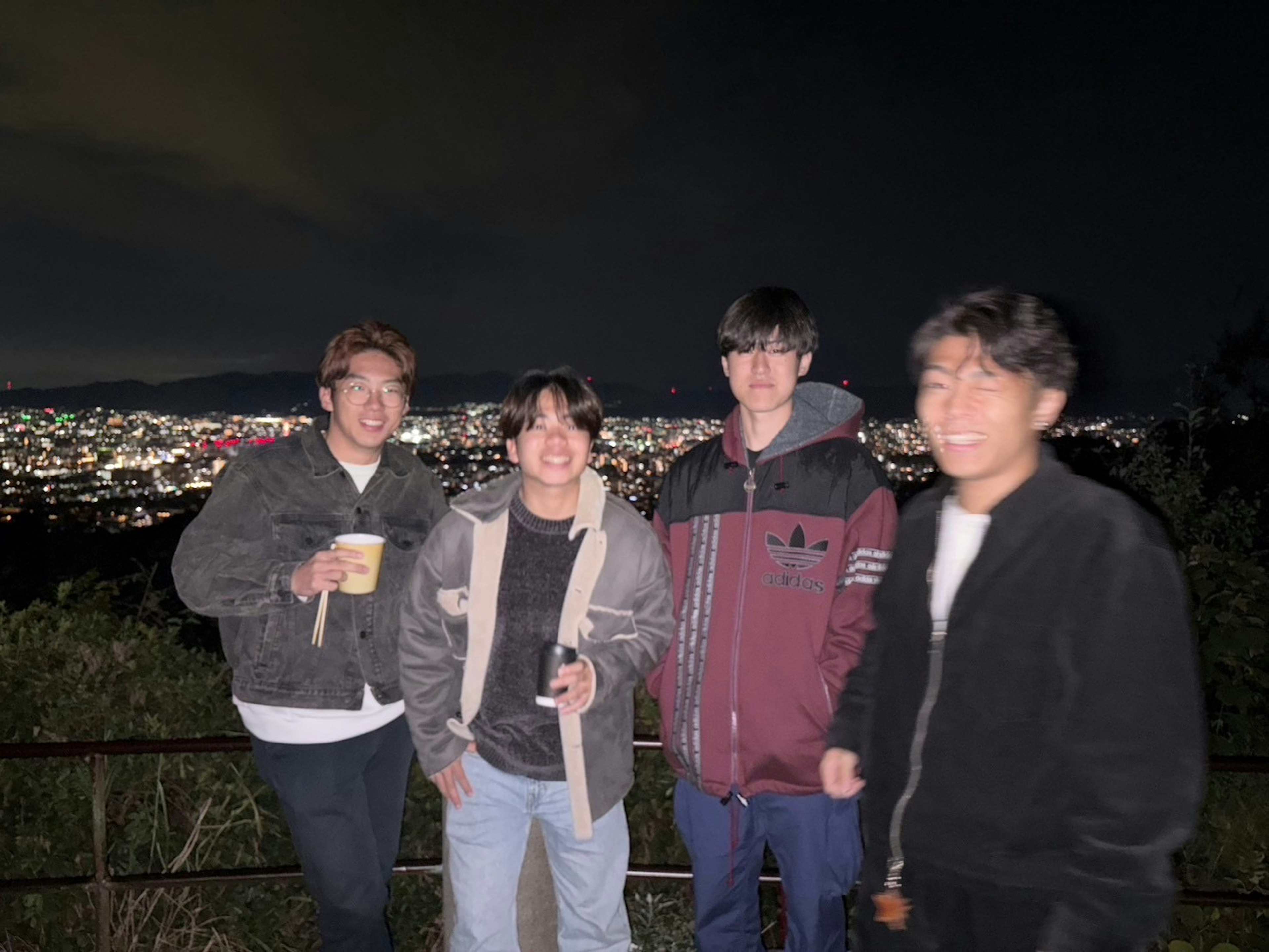 Gruppenfoto von jungen Leuten mit einer Stadtansicht bei Nacht