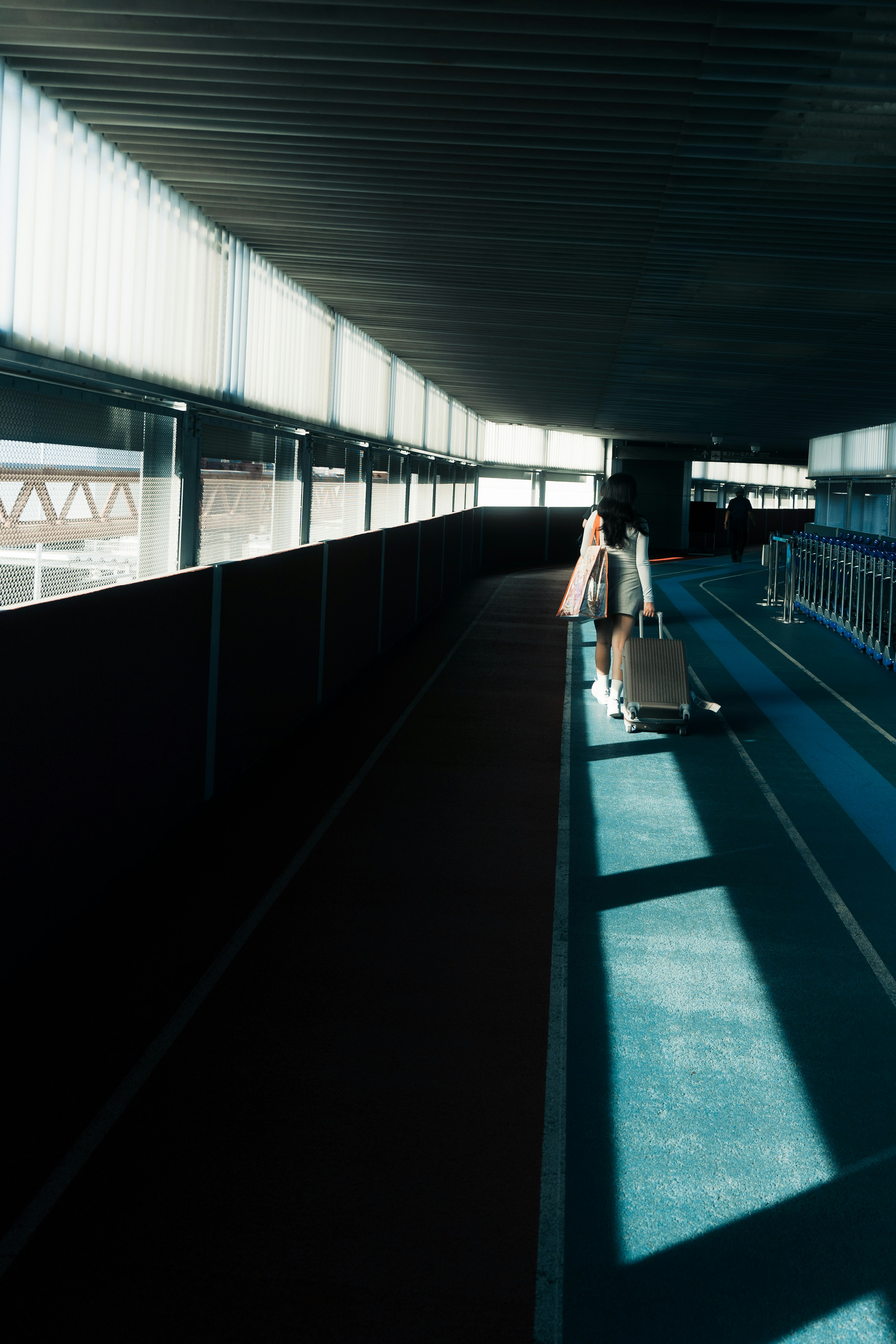 A person walking with luggage in a brightly lit corridor