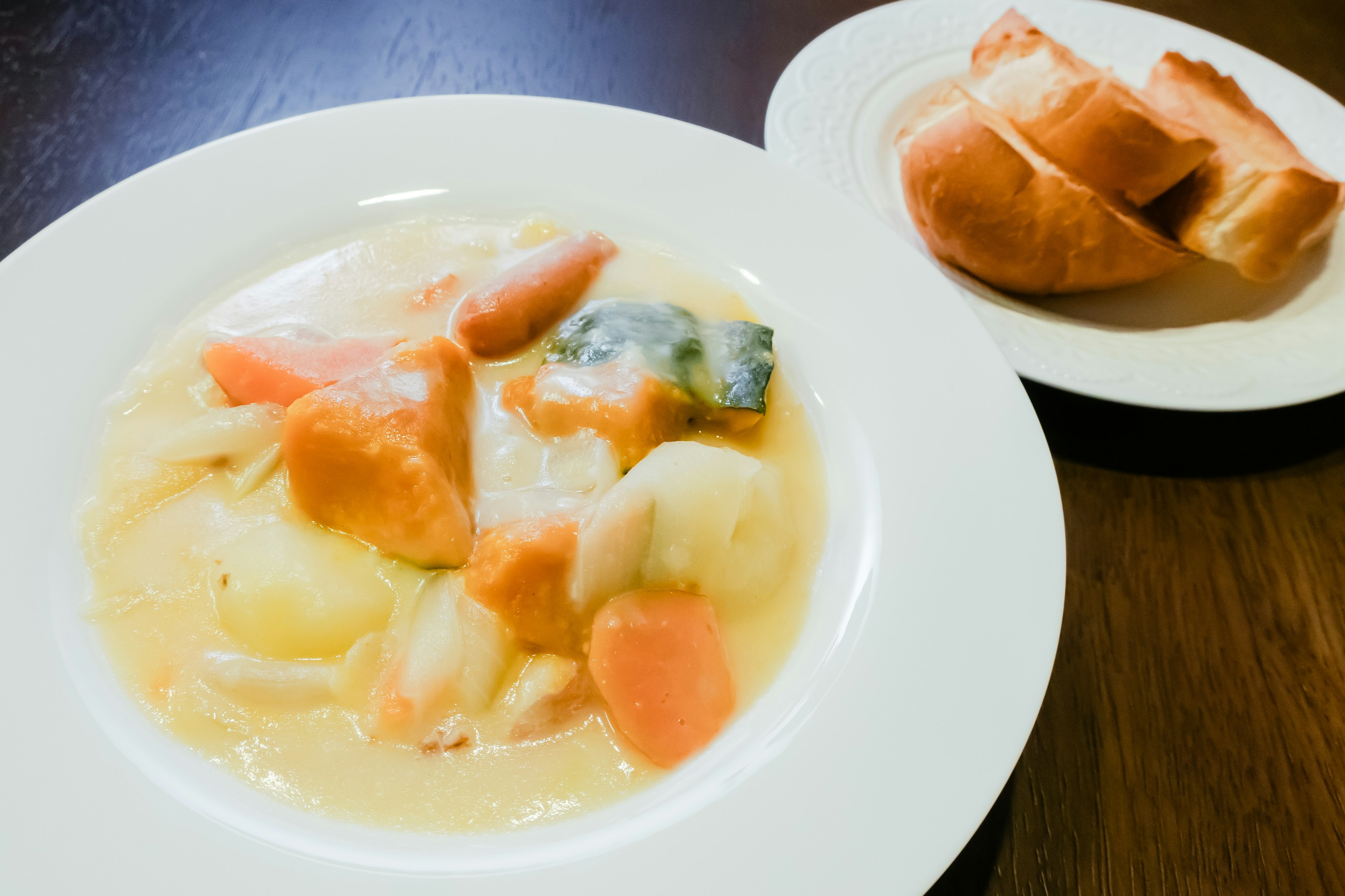 Cremige Suppe mit Gemüse und Brot serviert