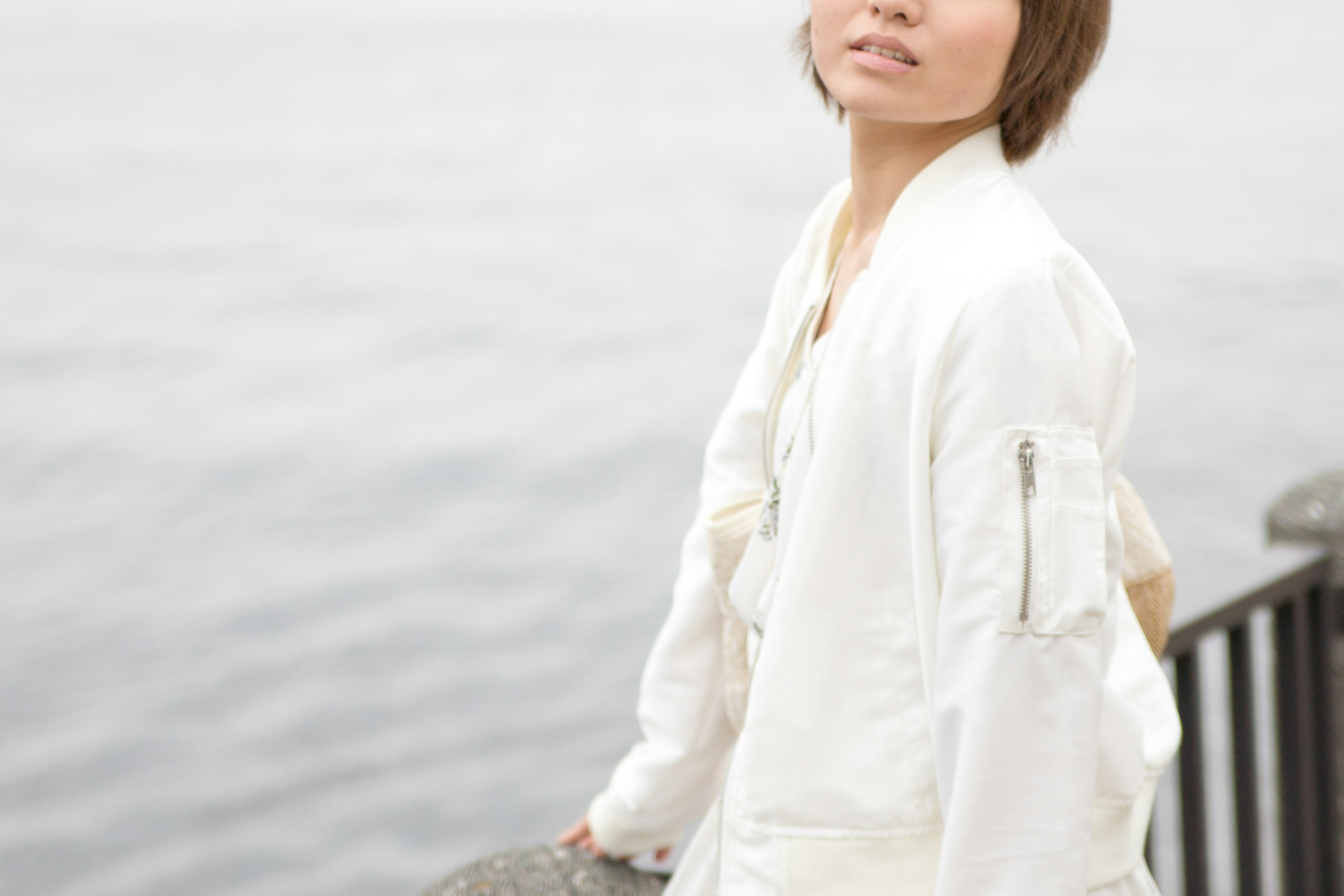 Portrait of a woman wearing a white jacket near the sea