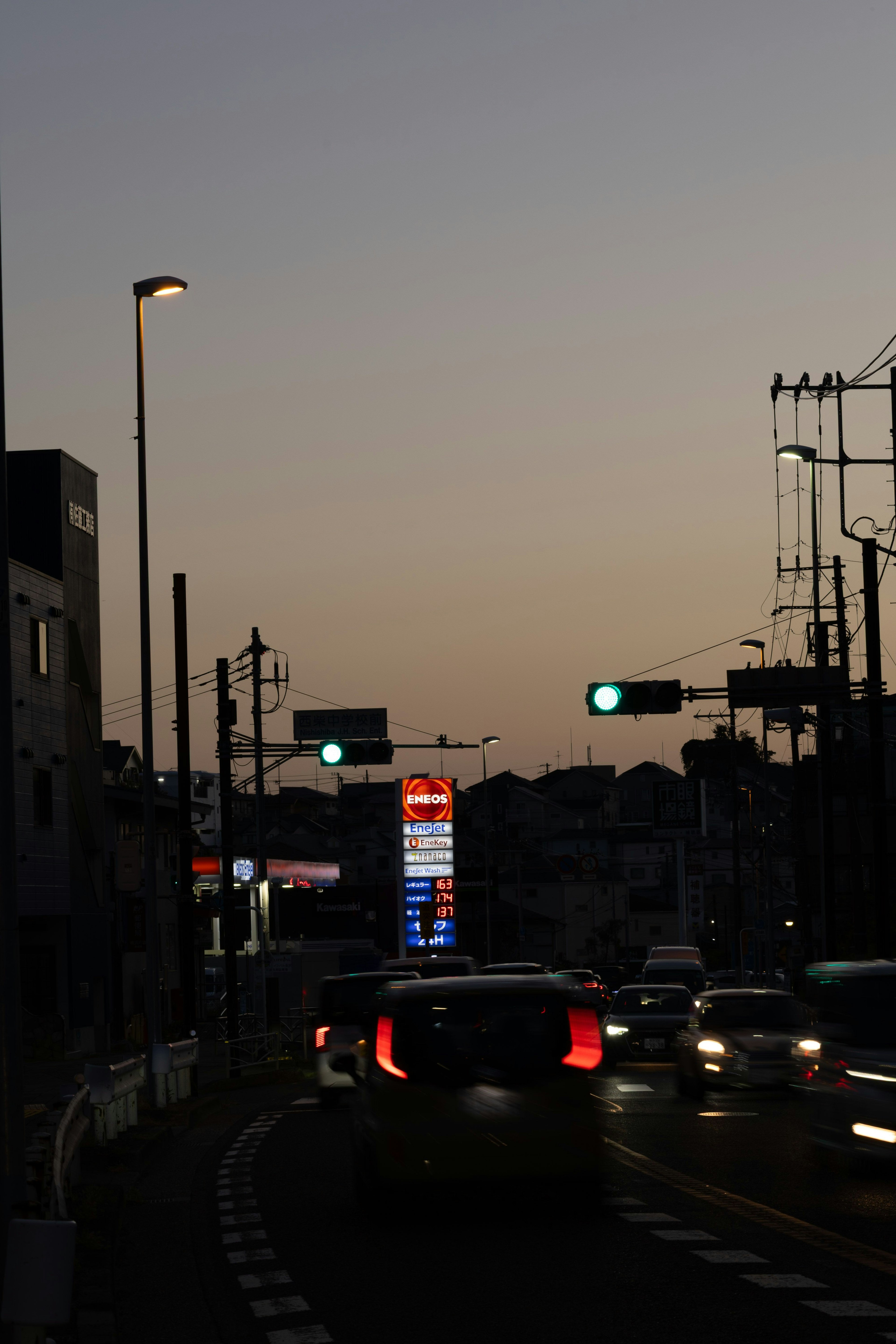 夕暮れ時の街の風景 車が通る道路と信号機が見える