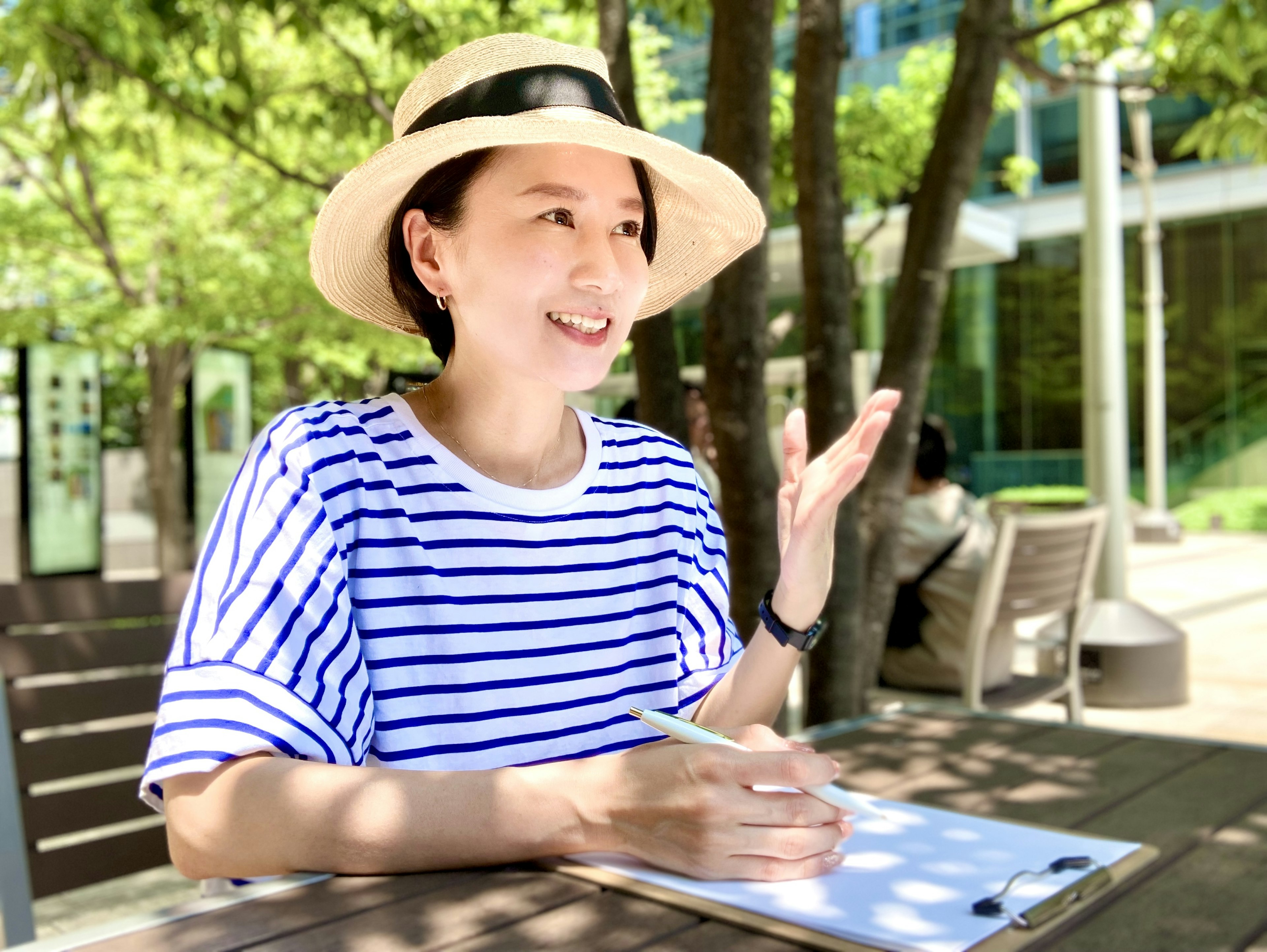 A woman wearing a striped shirt is happily talking outdoors