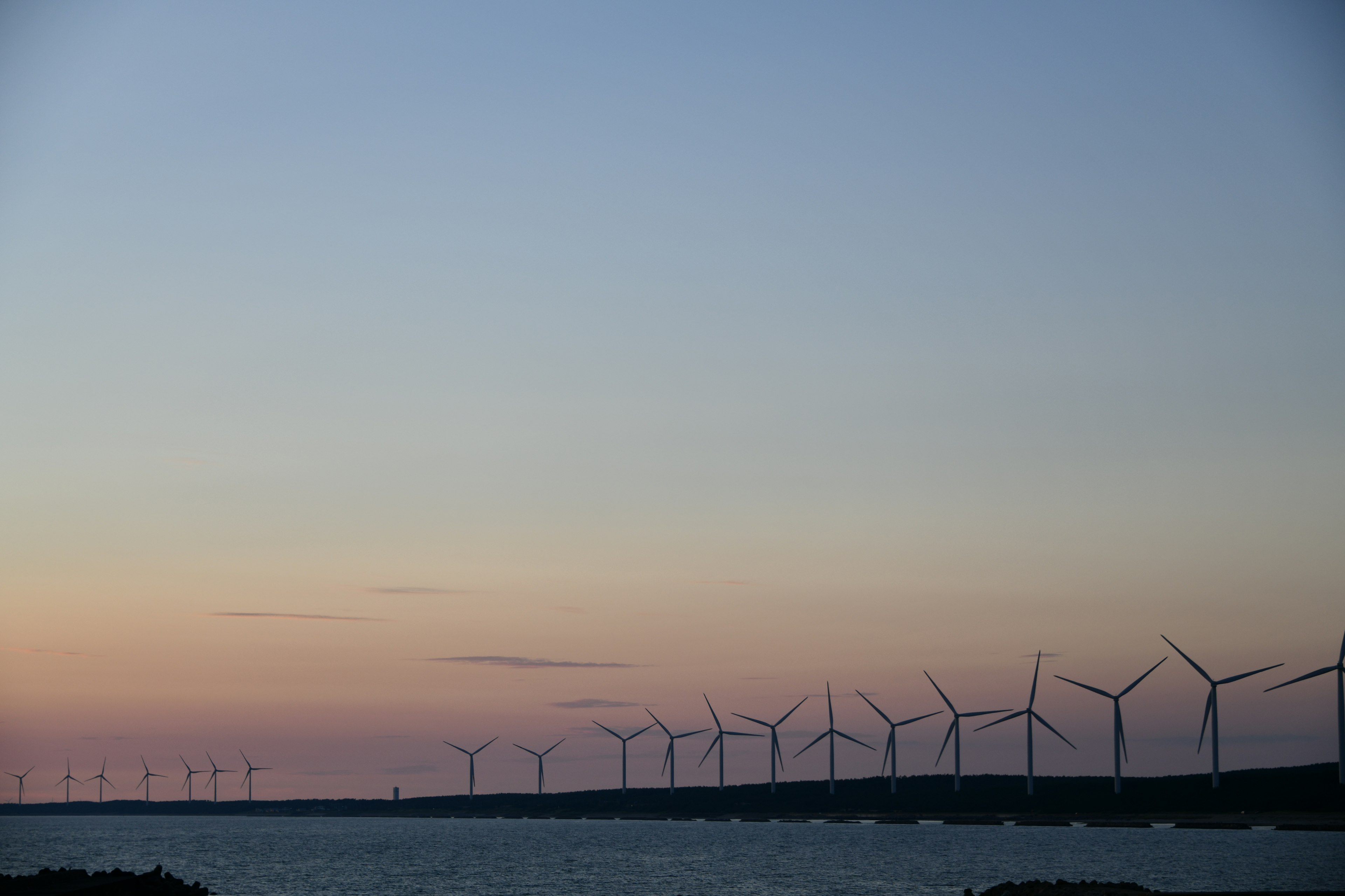 Coastal sunset with wind turbines in the distance