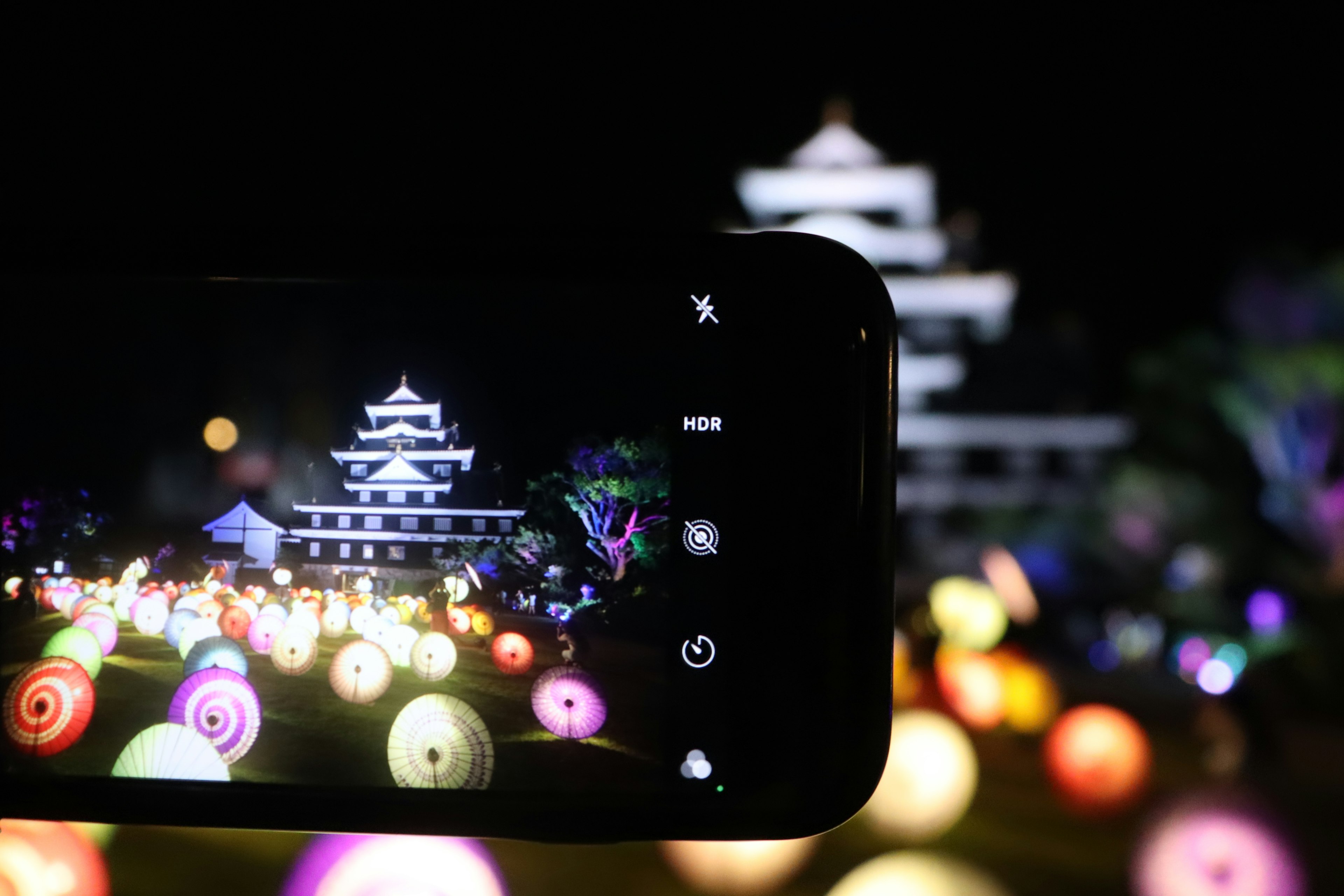 夜の風景を撮影したスマートフォンとカラフルなランタンが広がる光景