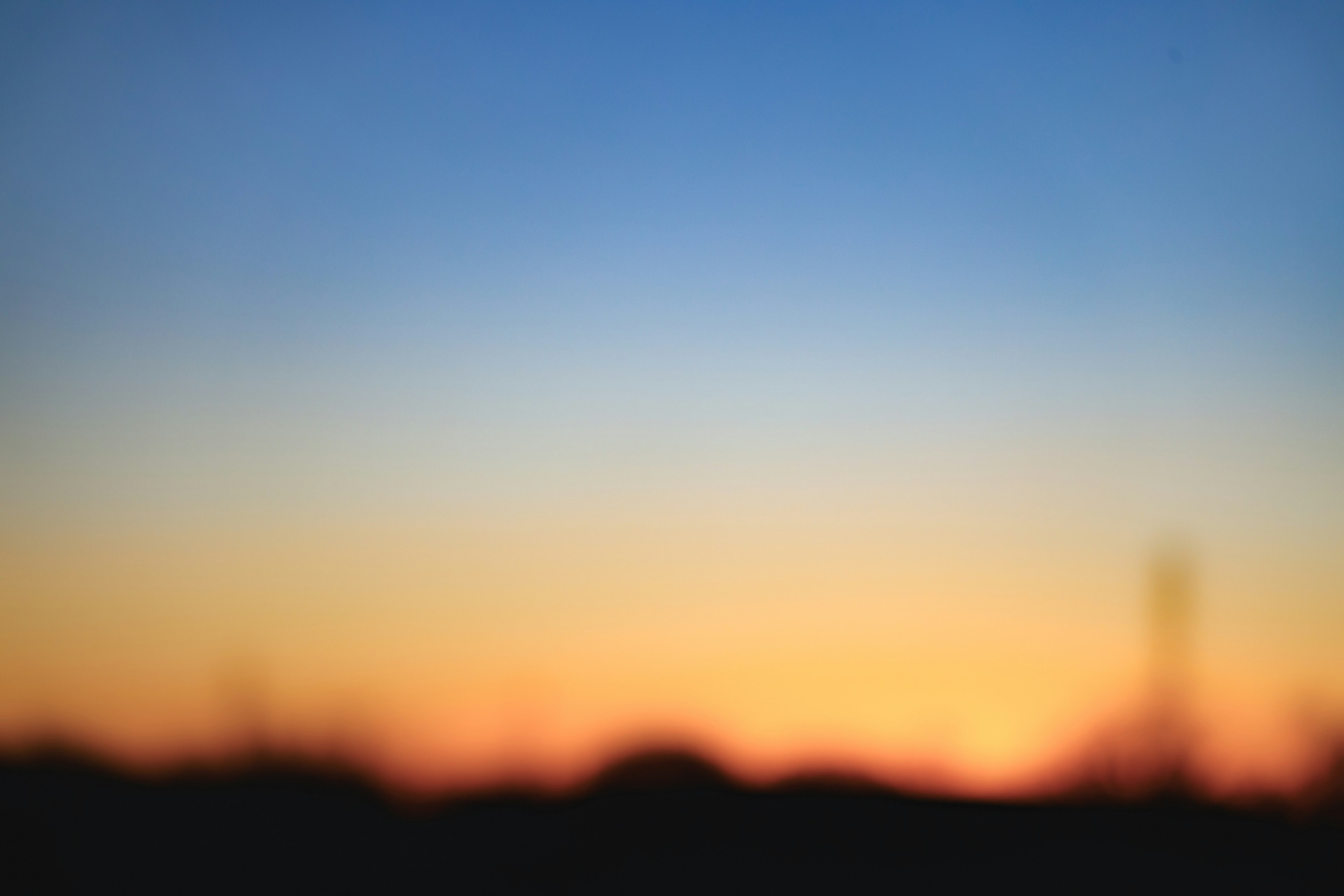 Blurred gradient of a sunset sky with silhouettes