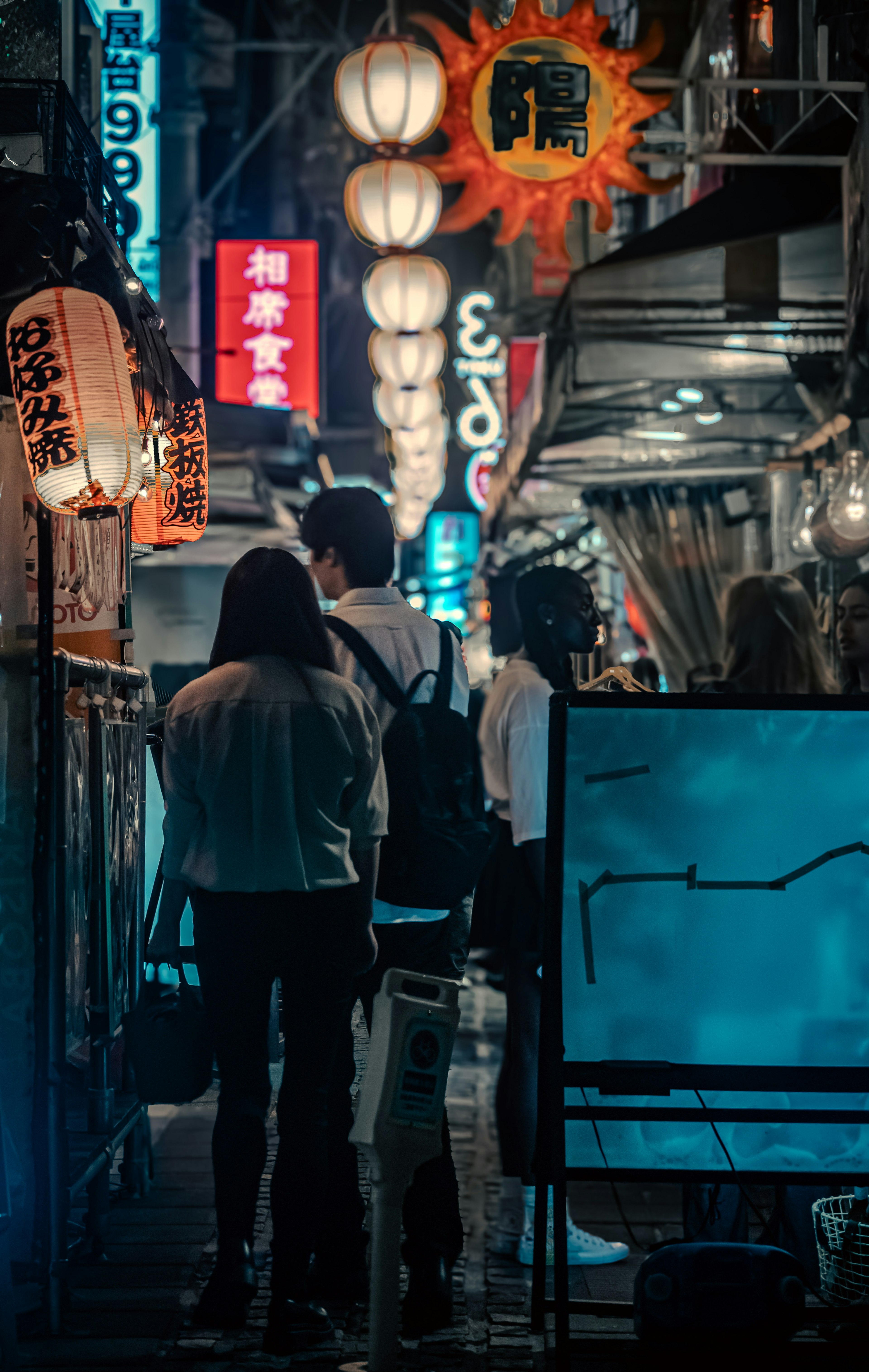 夜の街並みで提灯が光る日本の通りを歩く人々