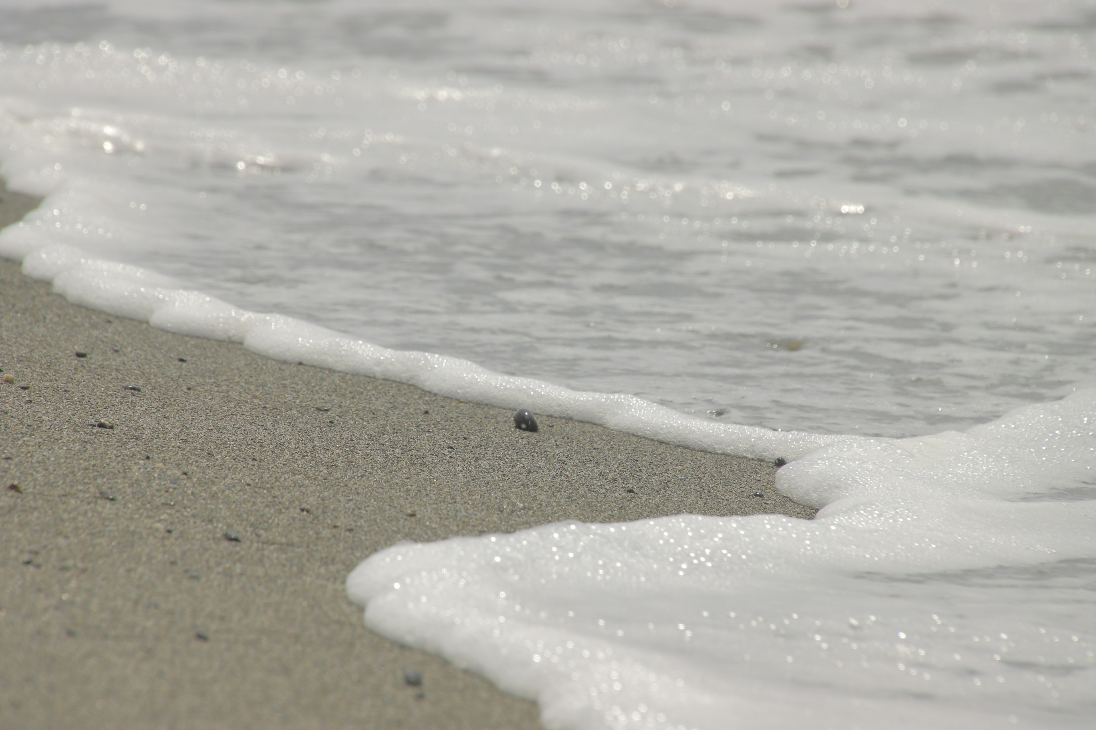 Wellen, die sanft an einen Sandstrand schlagen