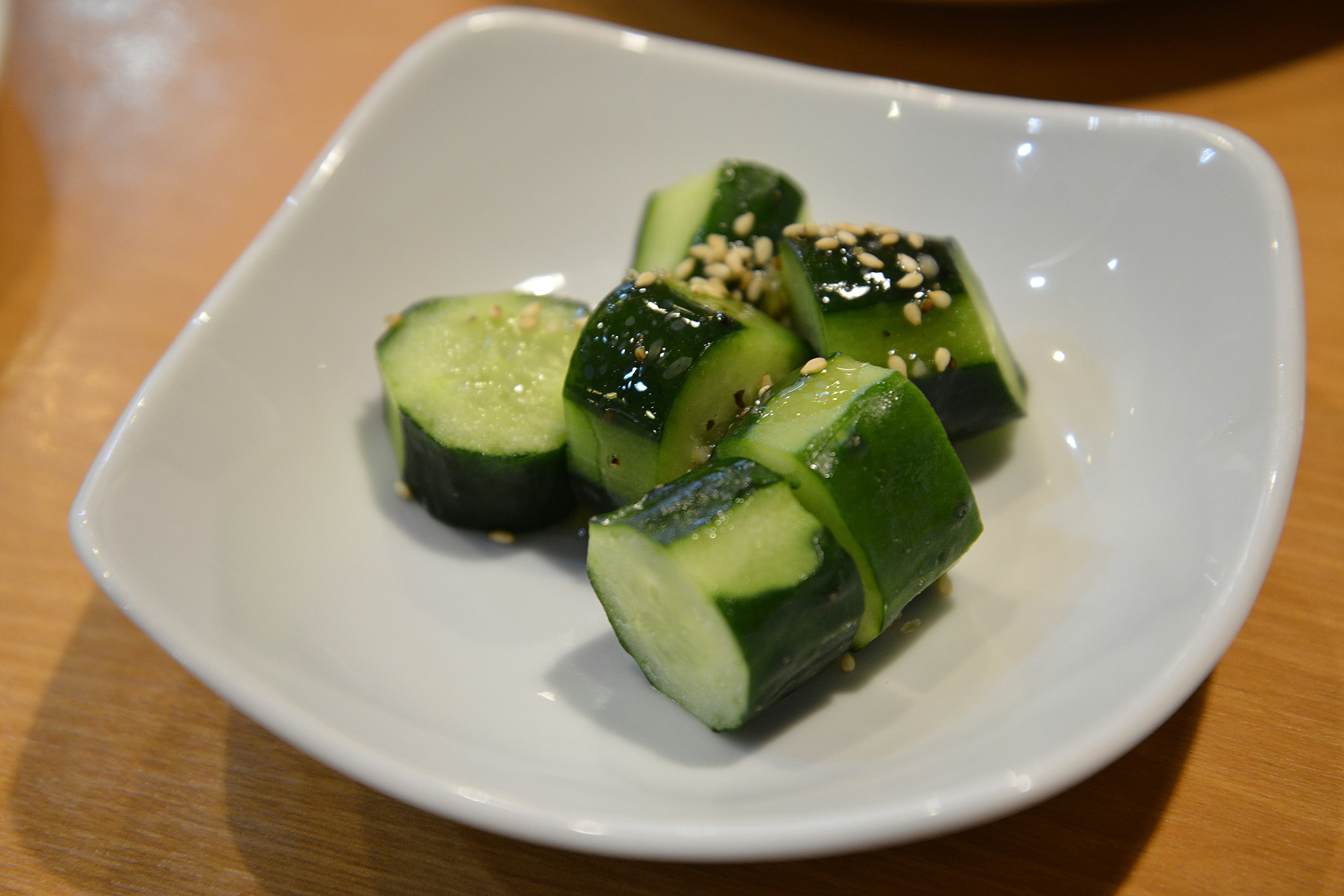 Cucumber salad served in a small dish with sesame seeds sprinkled on top