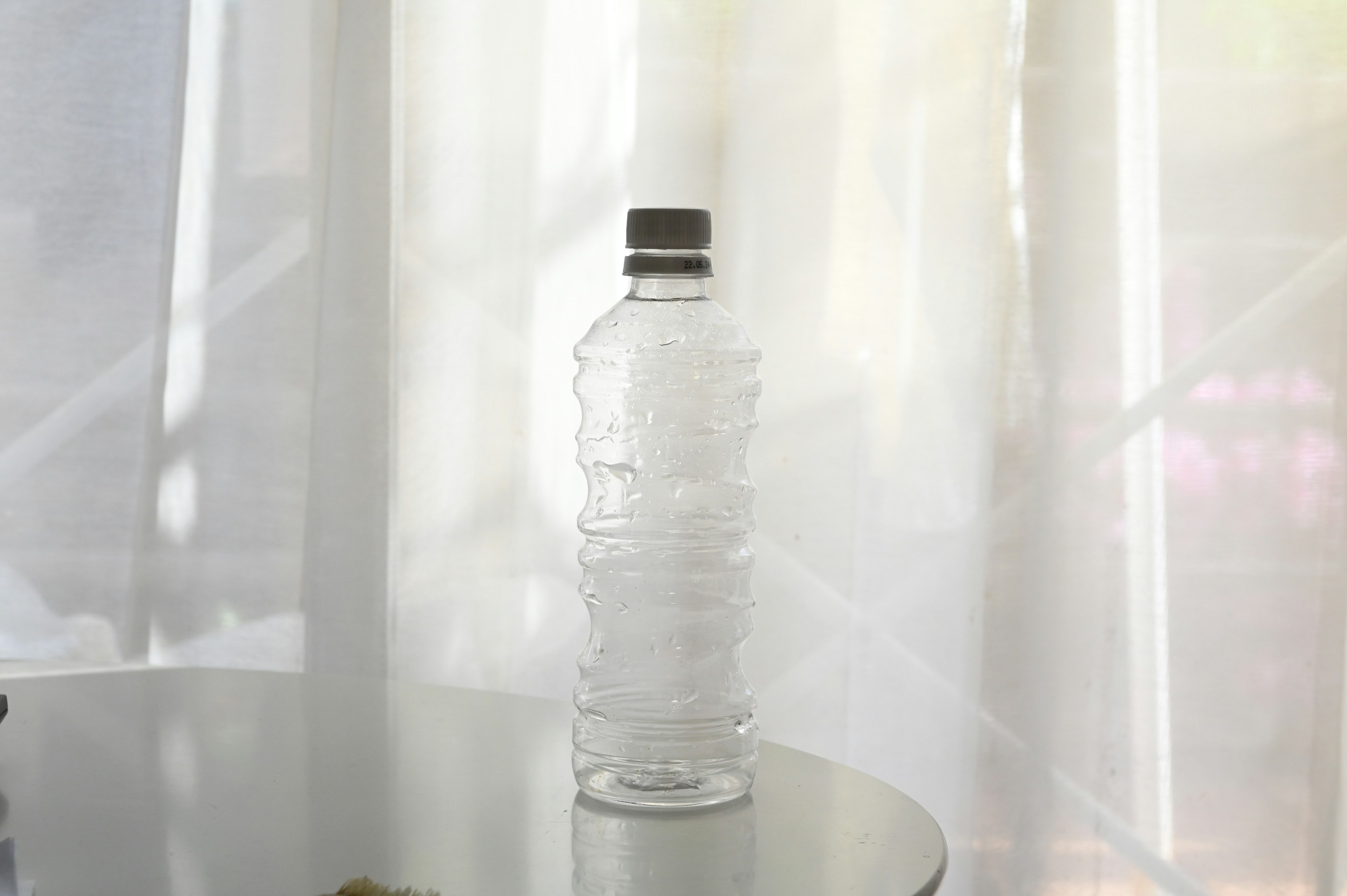 Eine klare Wasserflasche steht auf einem Tisch mit sanftem natürlichem Licht