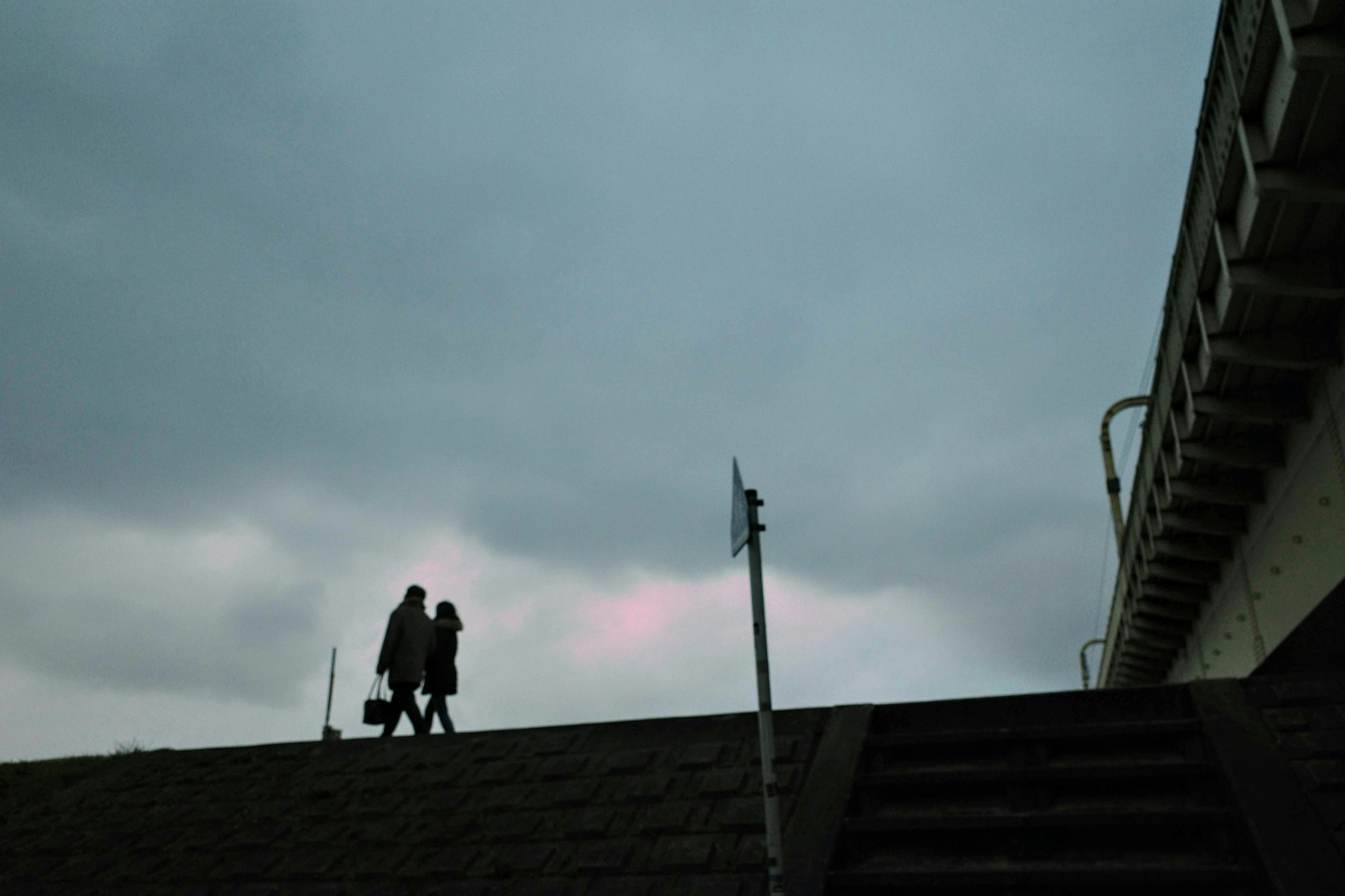 Silhouette of two people walking under dark clouds