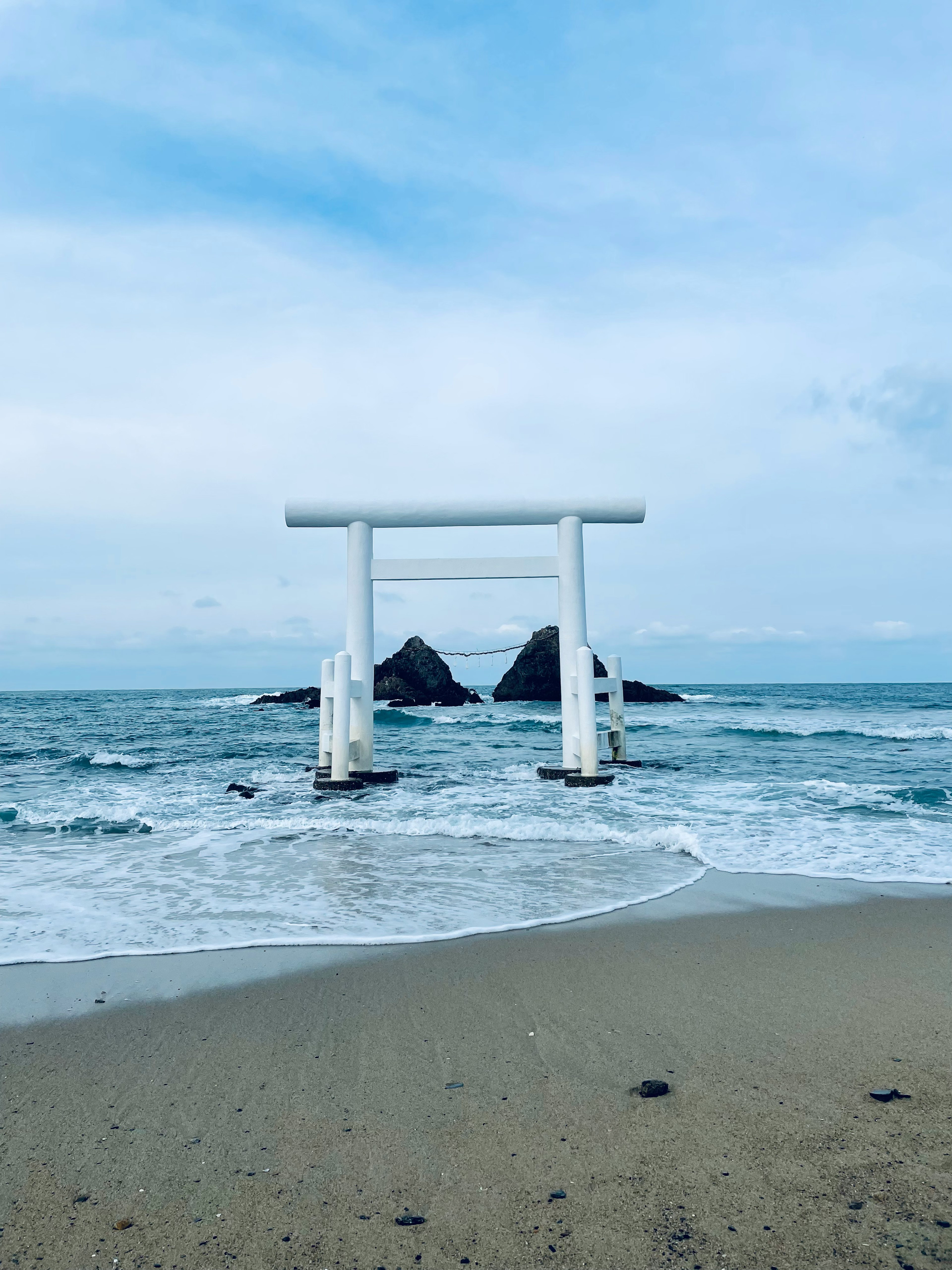 白い鳥居と岩が海に囲まれている風景