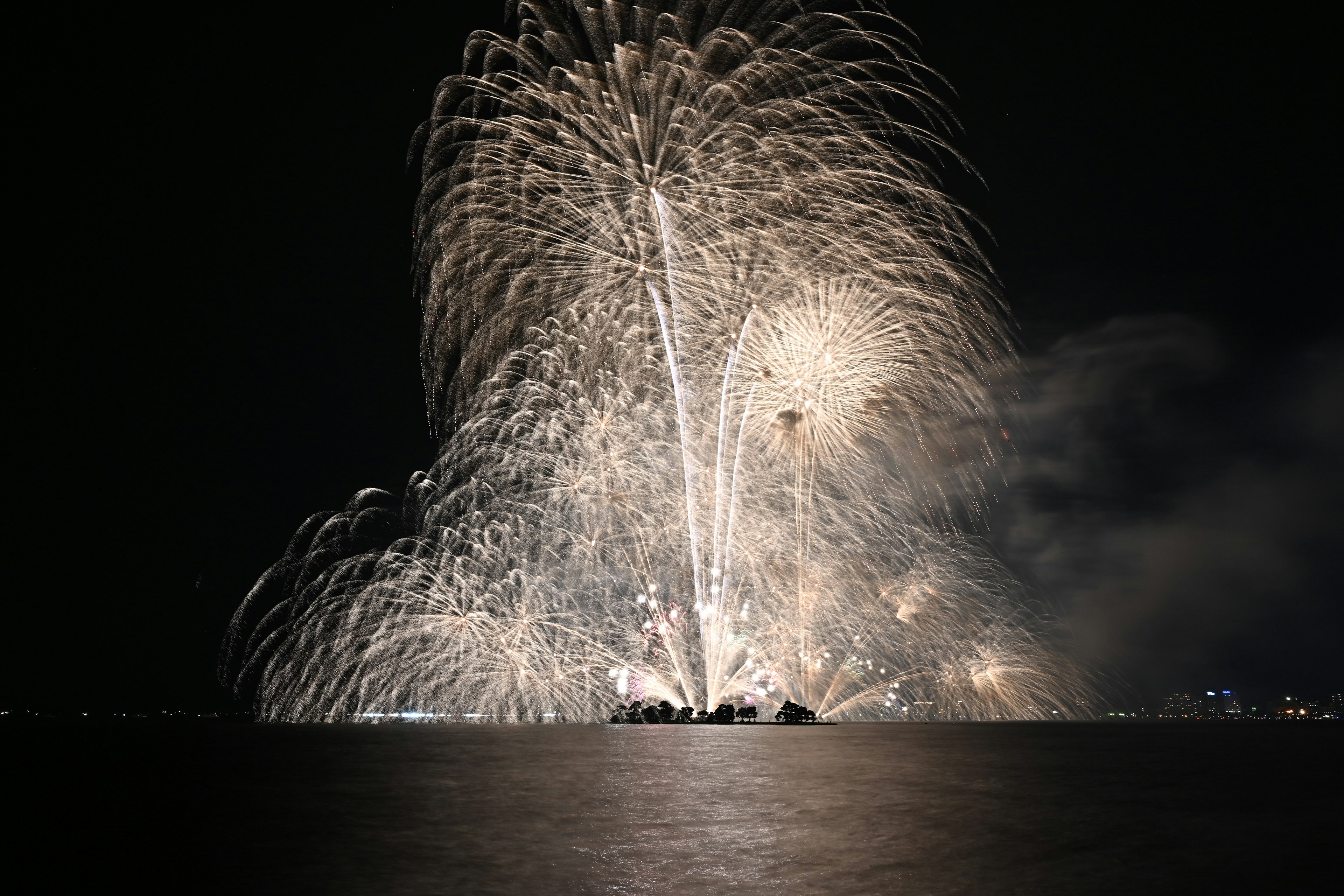 夜空に広がる花火の壮大なショーと水面の反射