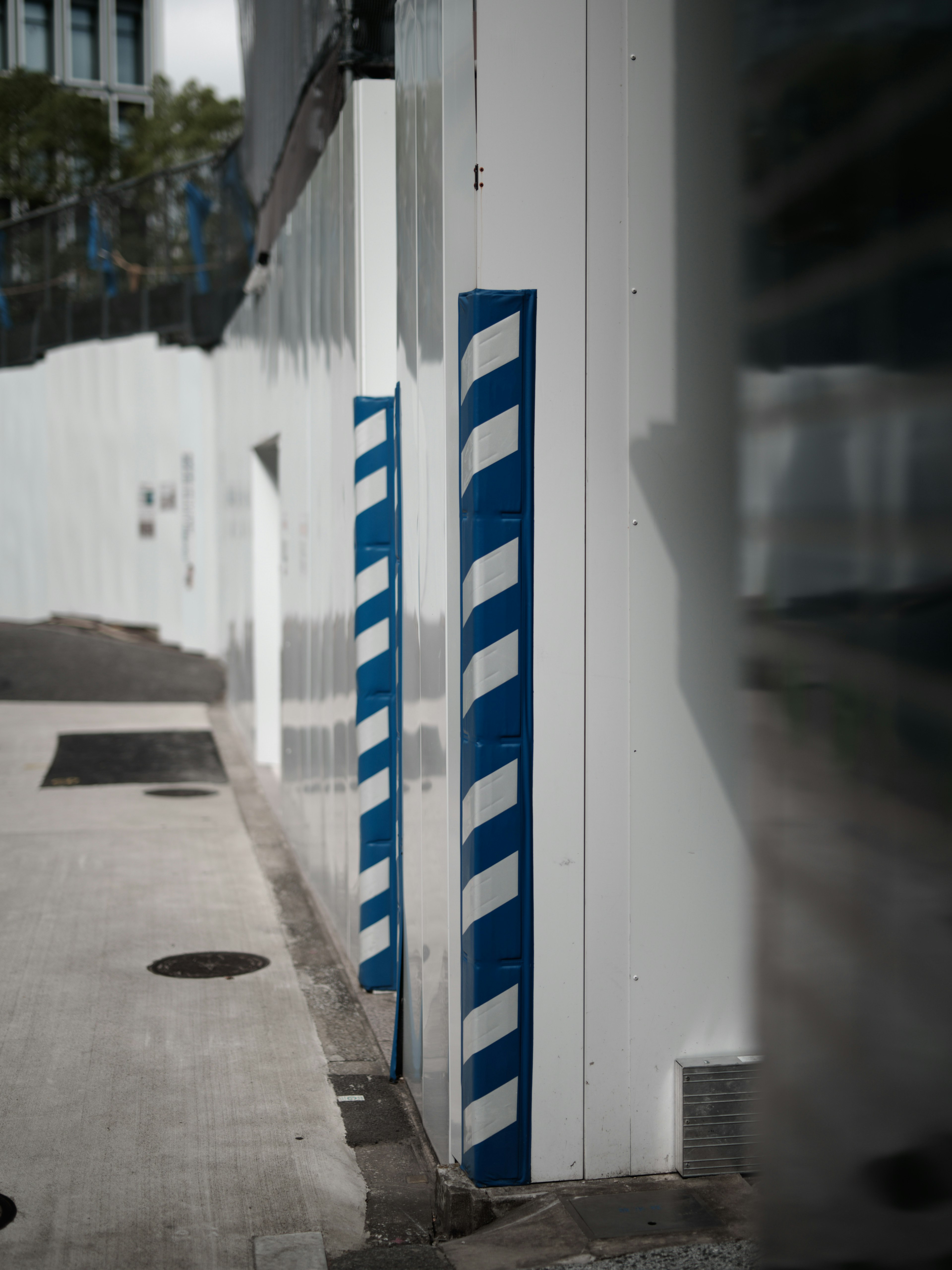 Straßenansicht mit blauen und weißen gestreiften Pfosten an einer weißen Wand