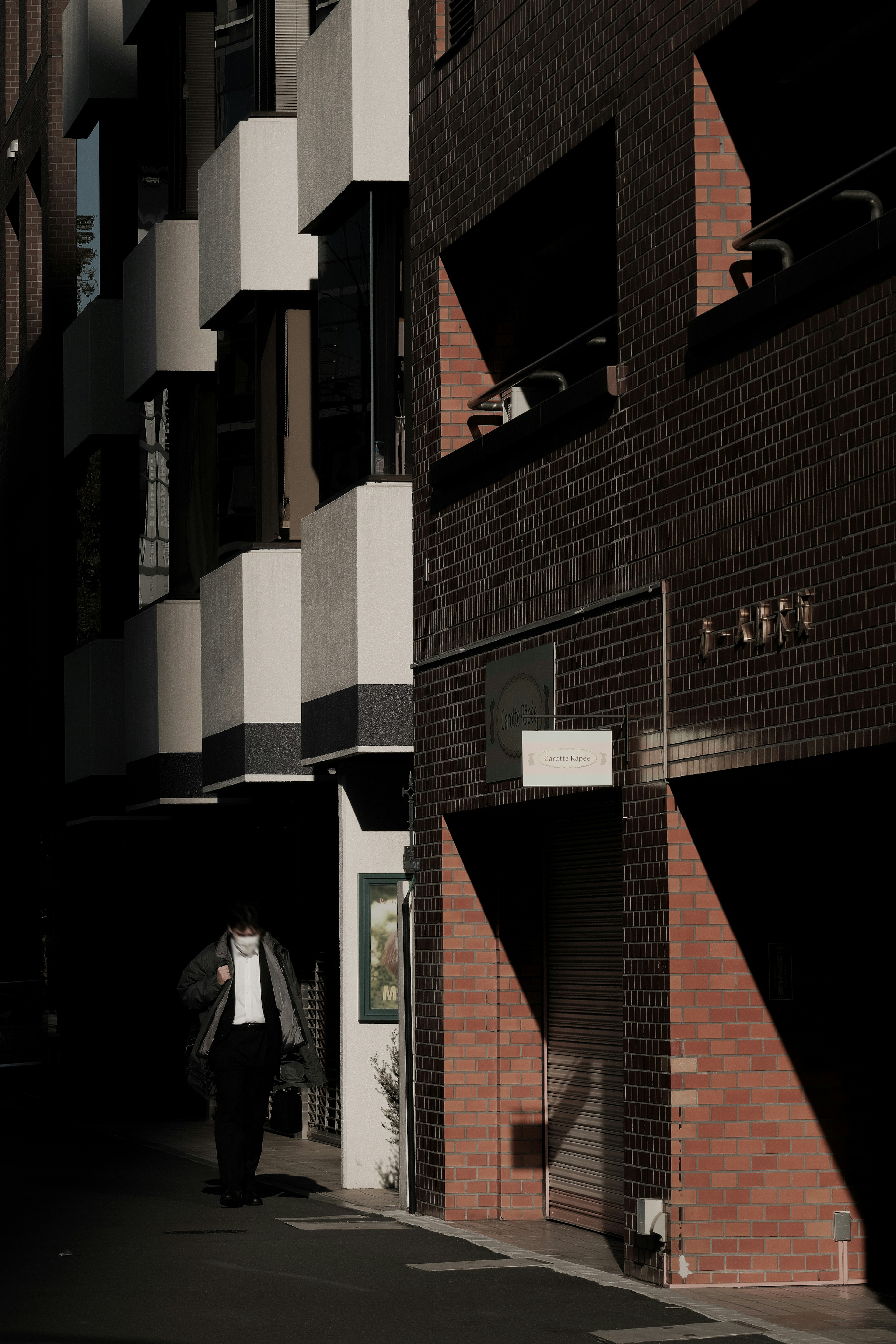 Una figura caminando en un callejón oscuro con arquitectura moderna