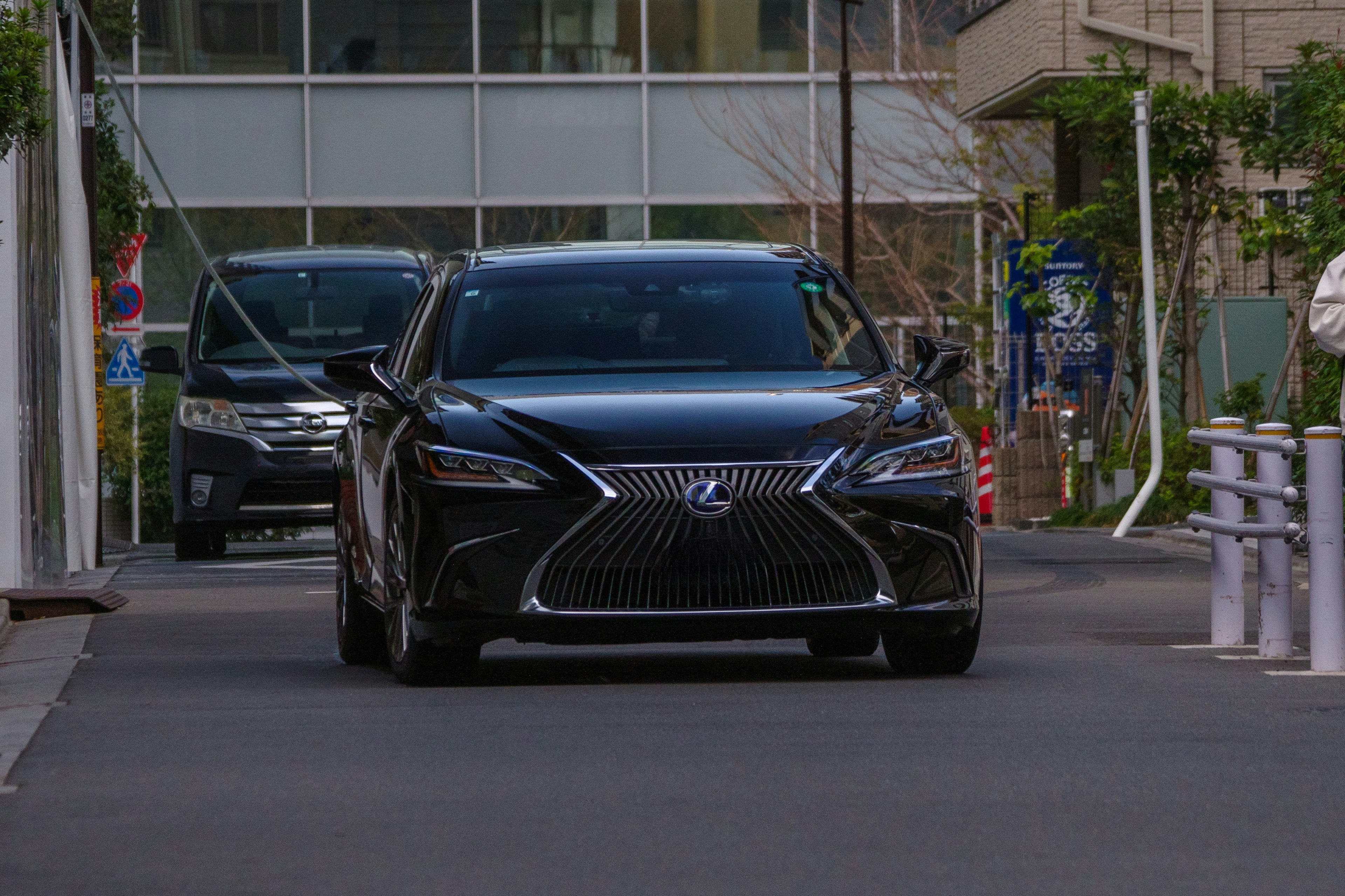 A black Lexus driving down an urban street