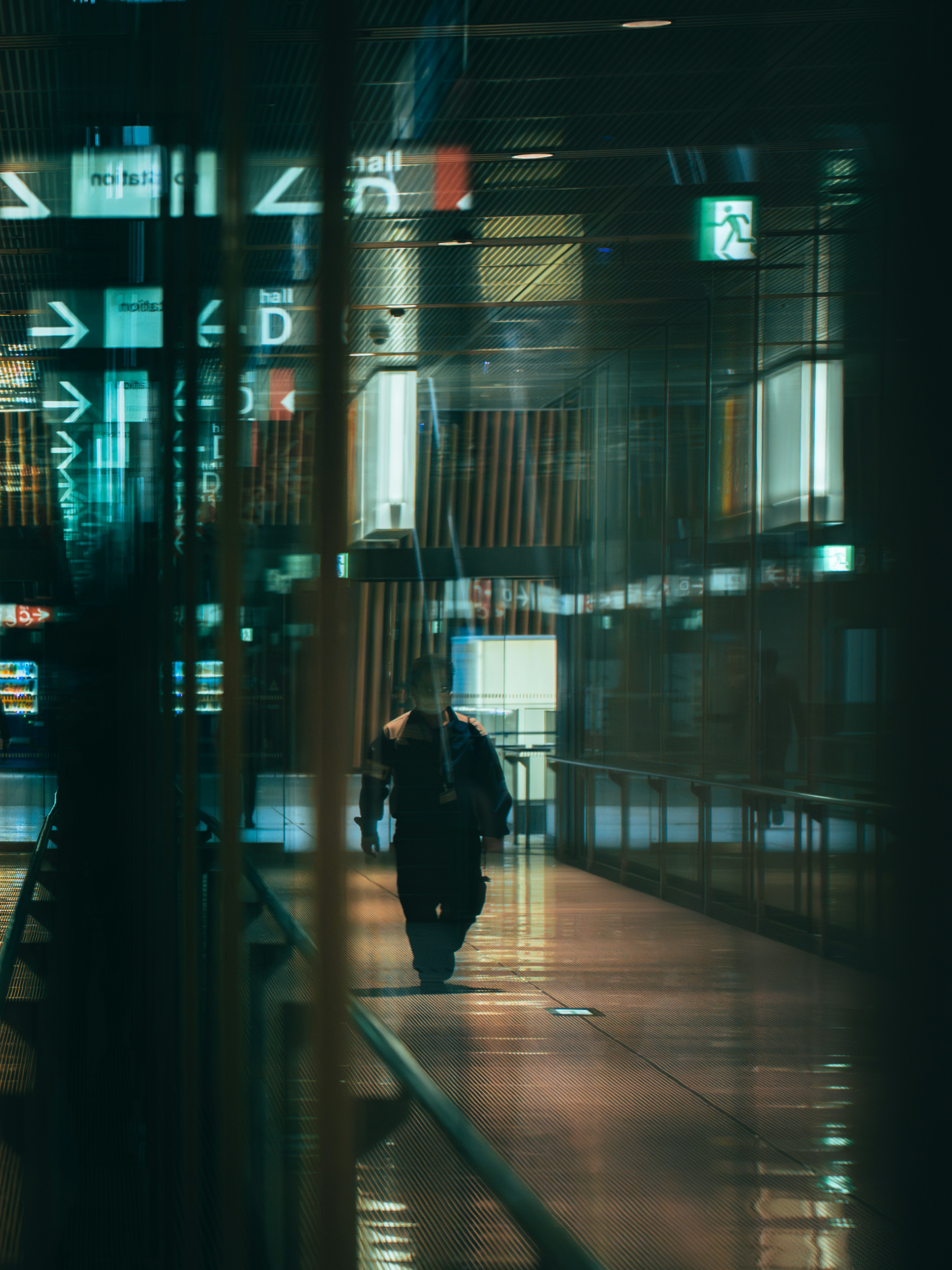 A silhouette walking in a dimly lit corridor of a building