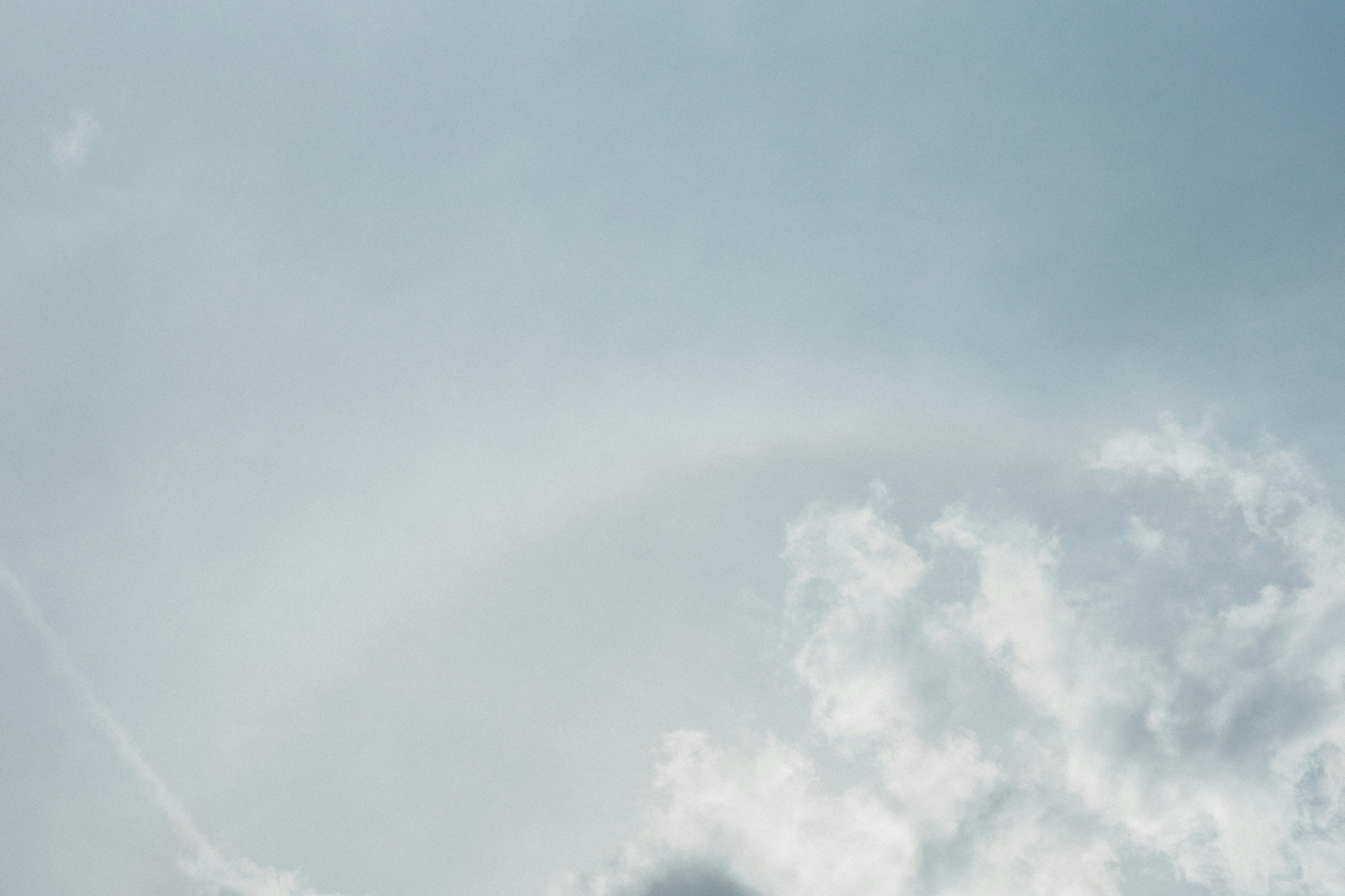 Schwacher Regenbogen, der über einen hellblauen Himmel mit sanften Wolken spannt