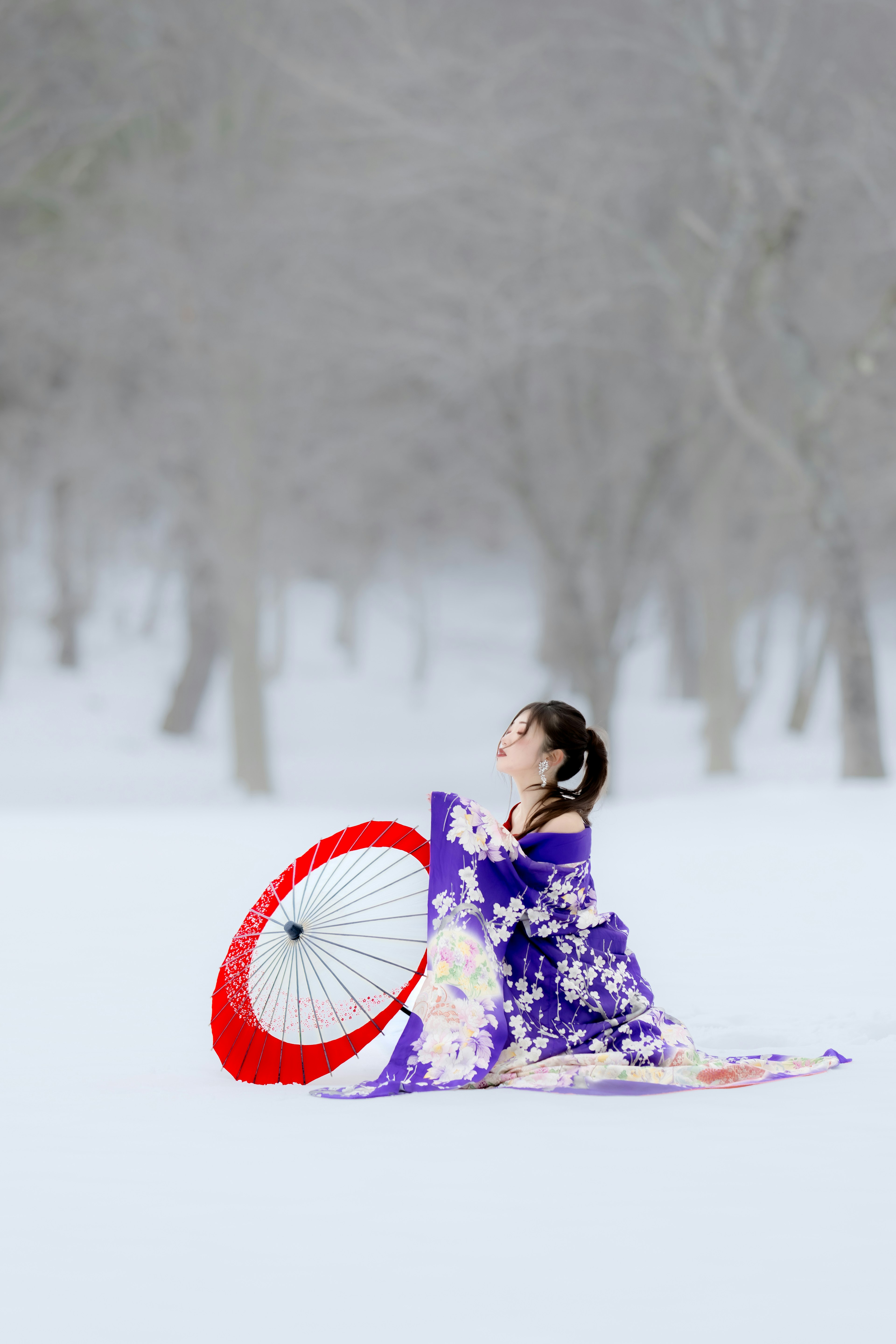 Donna in kimono con un ombrello rosso nella neve