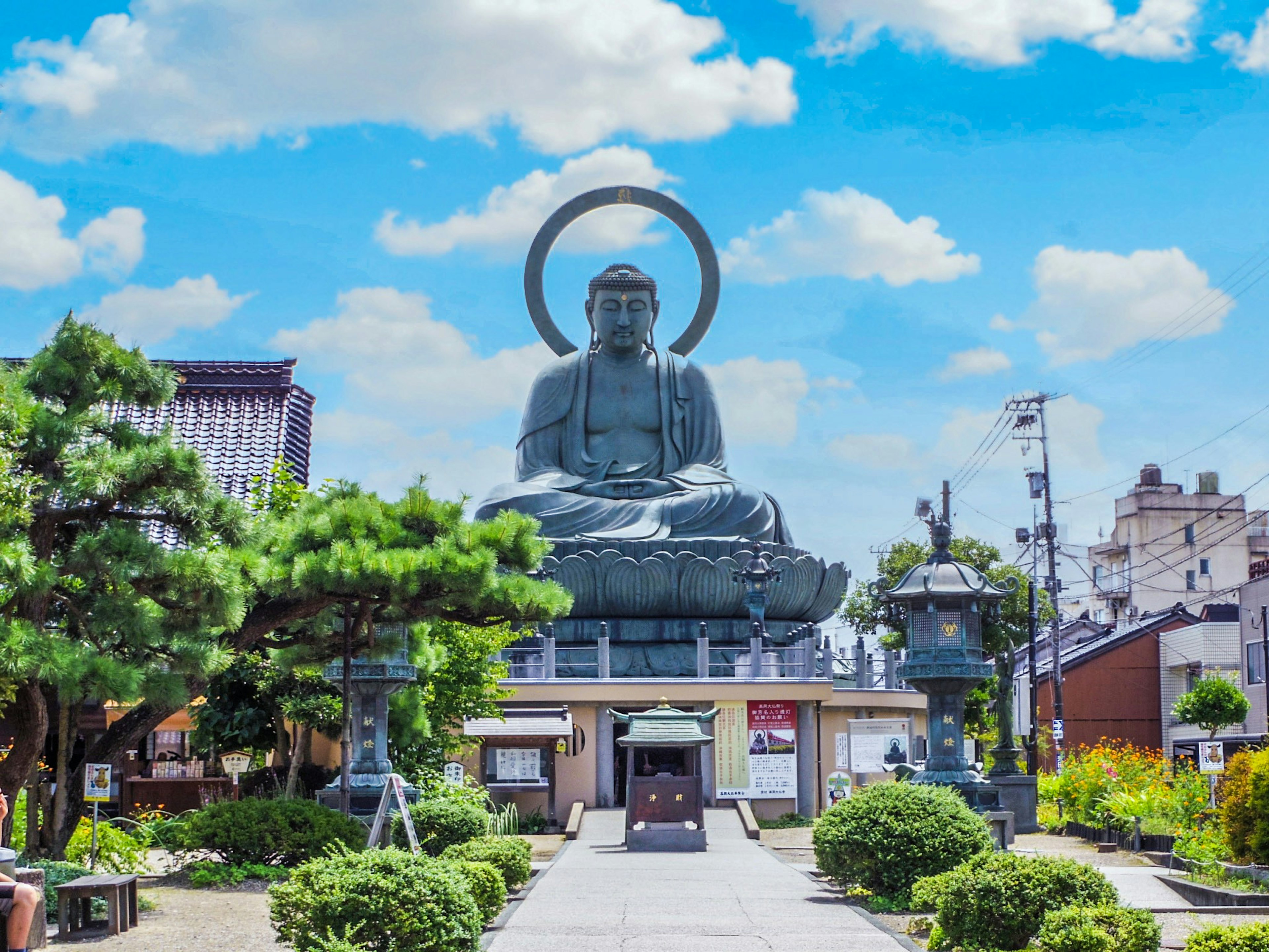 Large Buddha statue under a blue sky with a beautiful garden