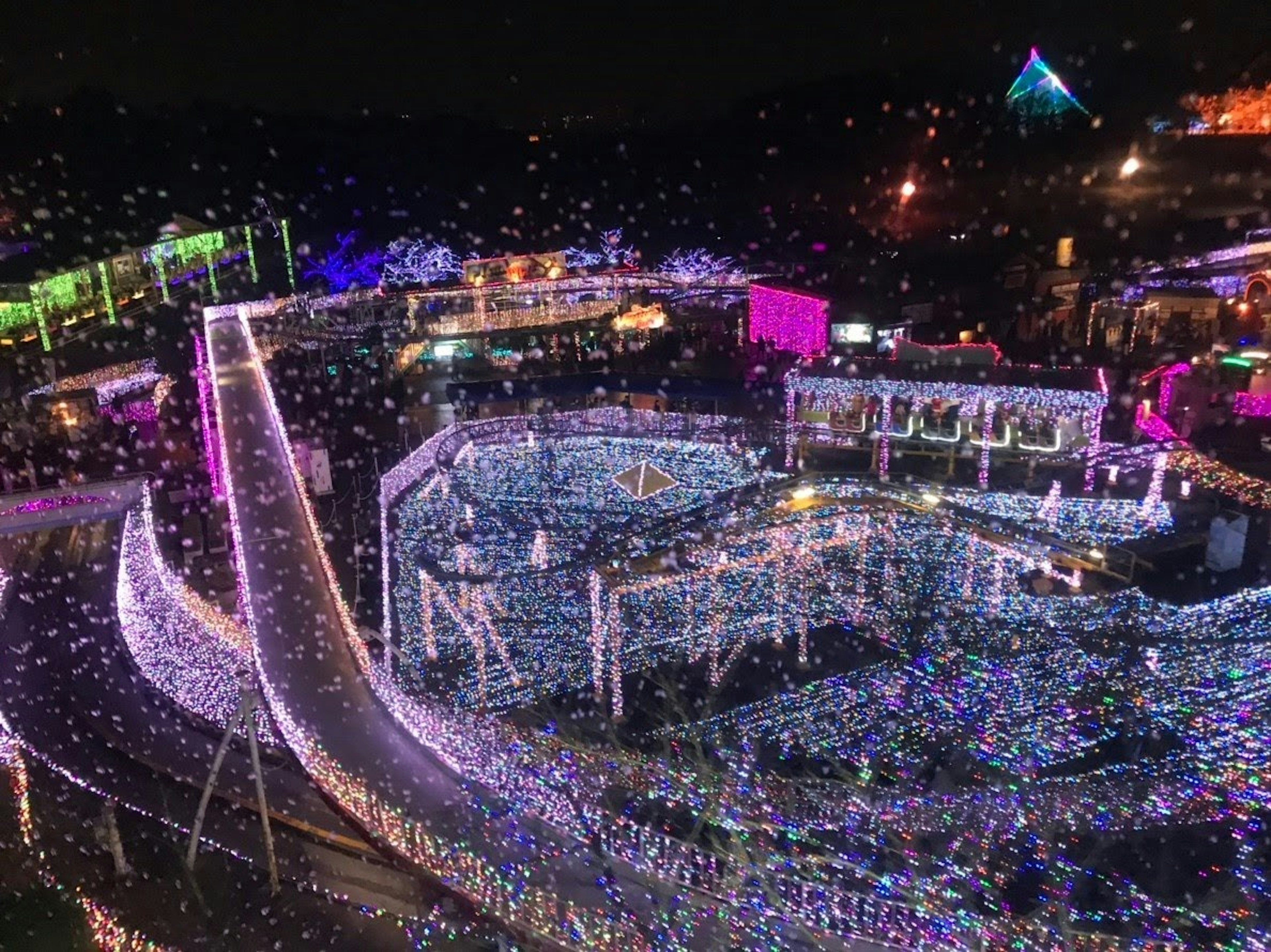 Aerial view of a theme park illuminated with colorful lights at night