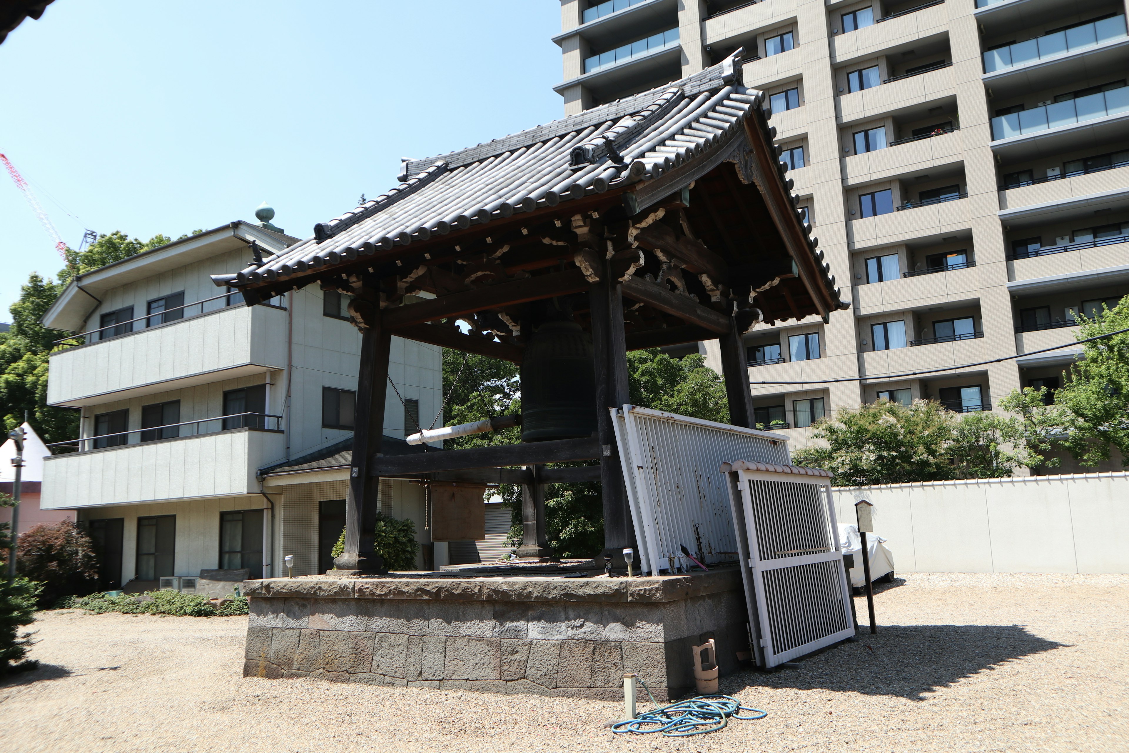 Traditional temple bell tower in a residential area with modern high-rise buildings