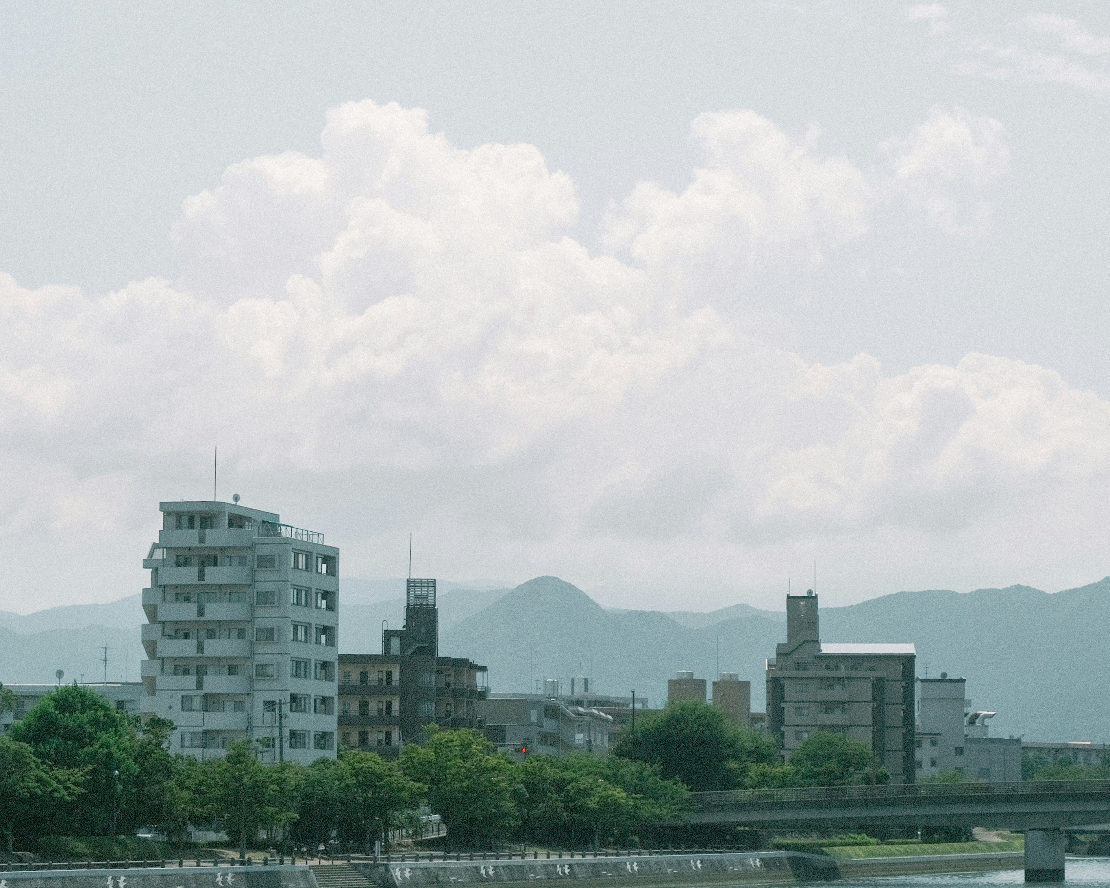 Urban landscape near the river featuring tall buildings and mountains