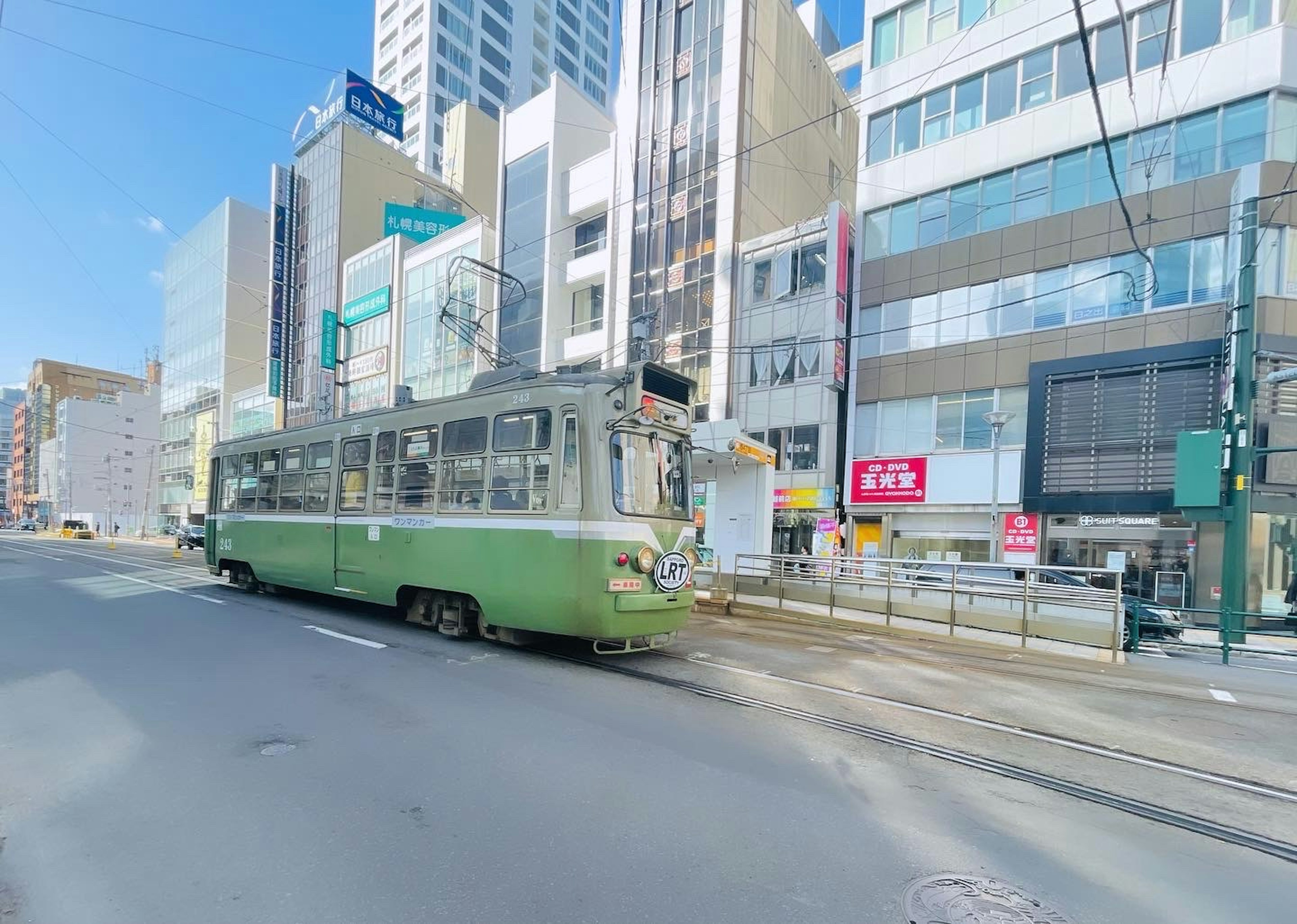 街中を走る緑色の路面電車と近代的なビル群