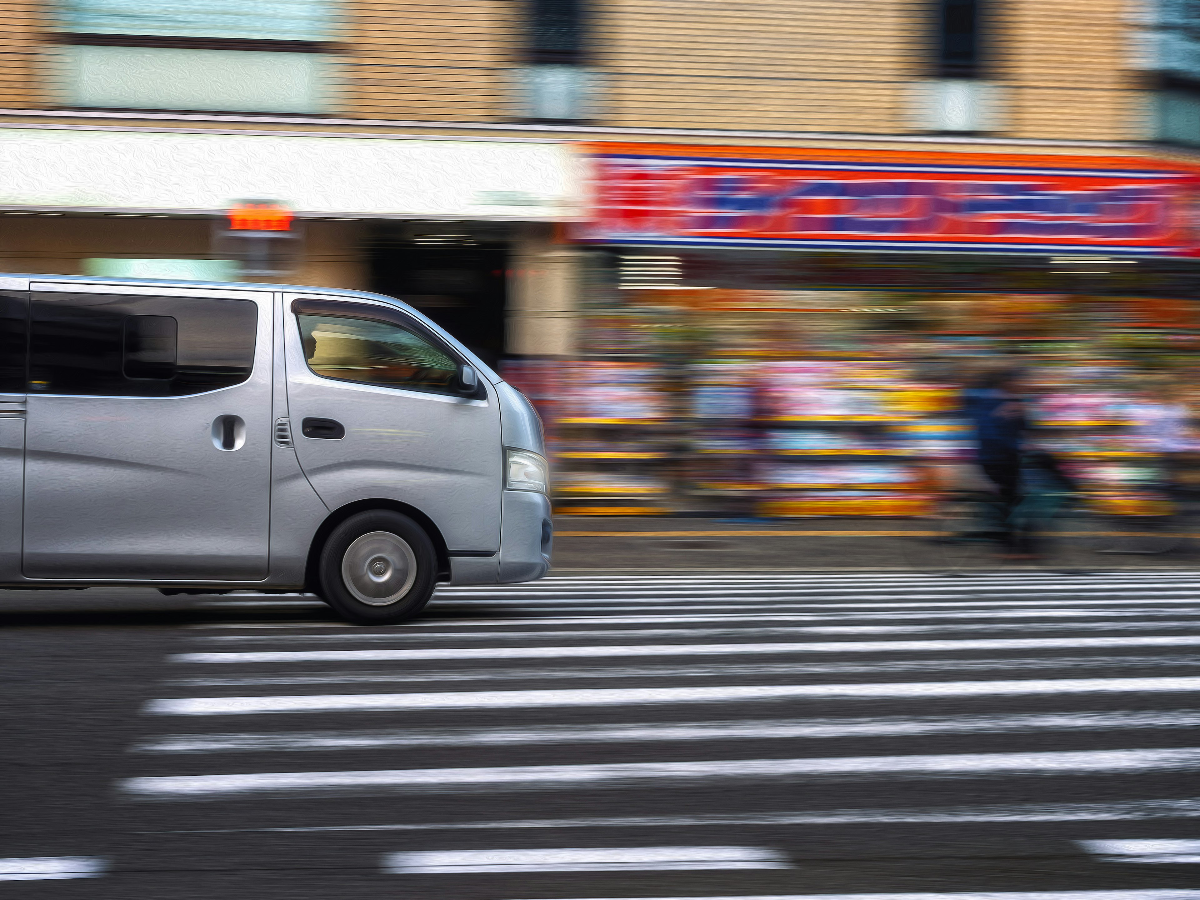 銀色廂型車在城市場景的斑馬線前快速駛過