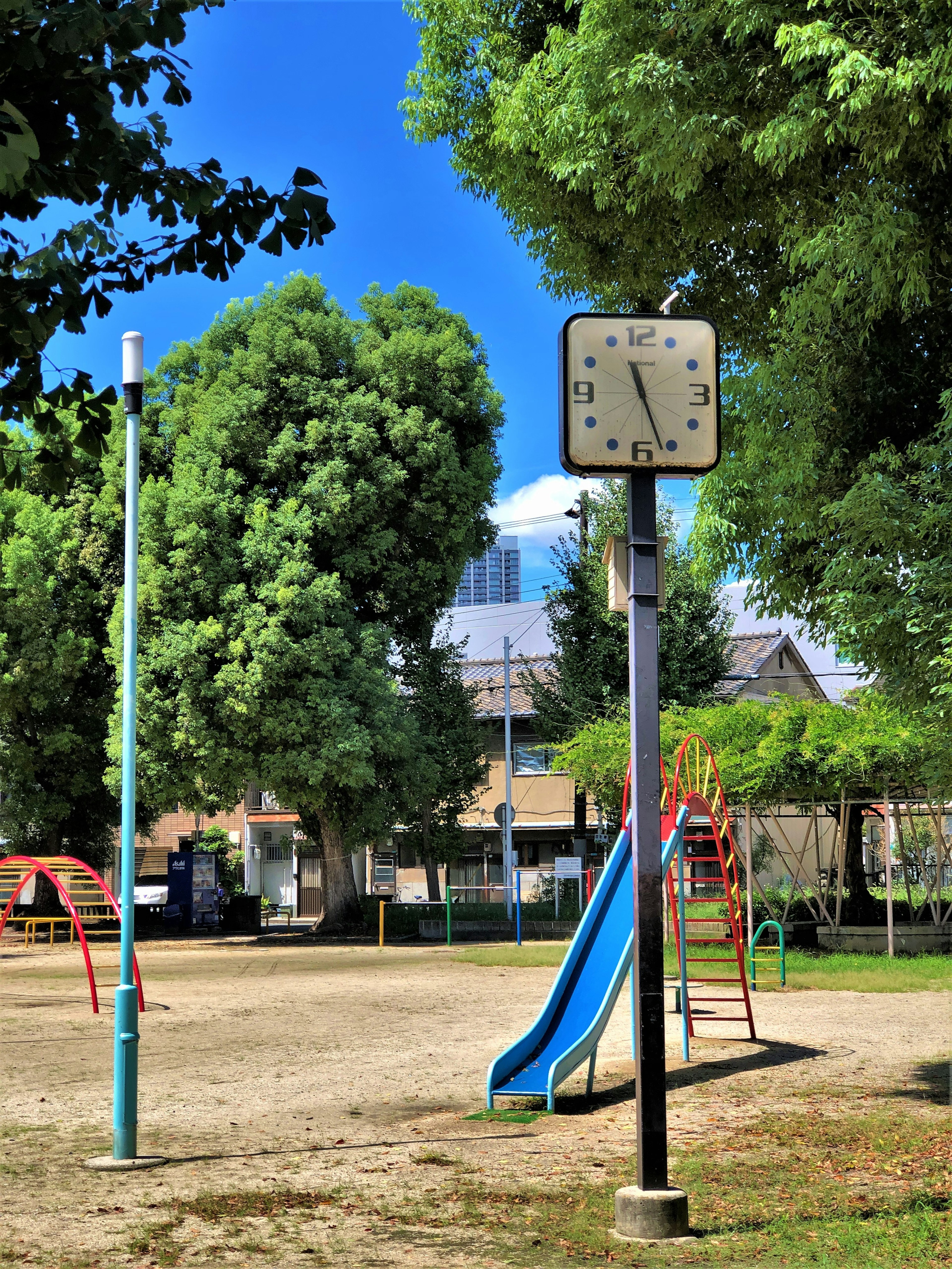 Escena de parque infantil con un tobogán azul y un reloj