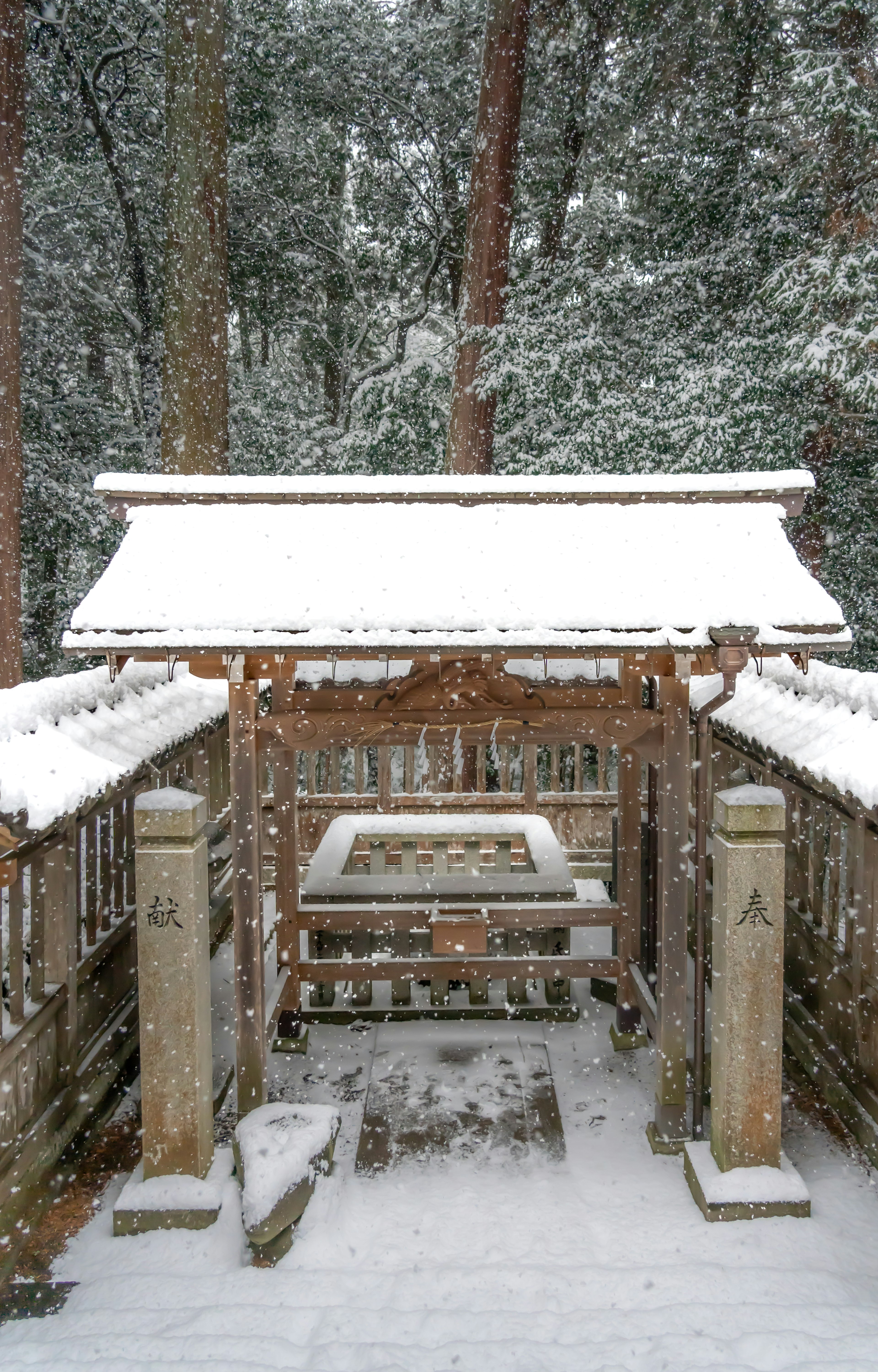 Ein schneebedeckter Schreingang mit Steinsäulen und Holzstruktur