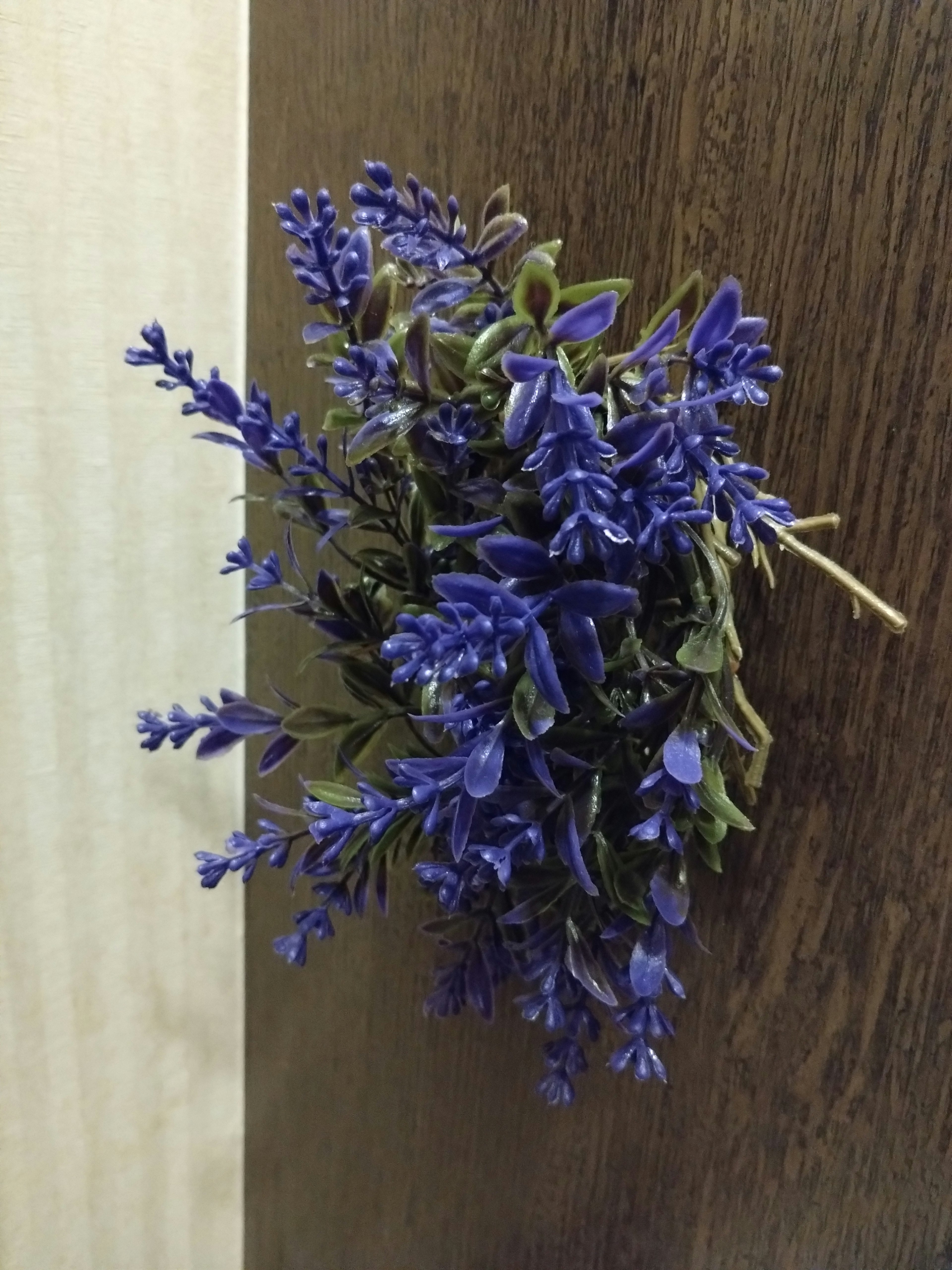 Un ramo de flores moradas pegado a una puerta de madera