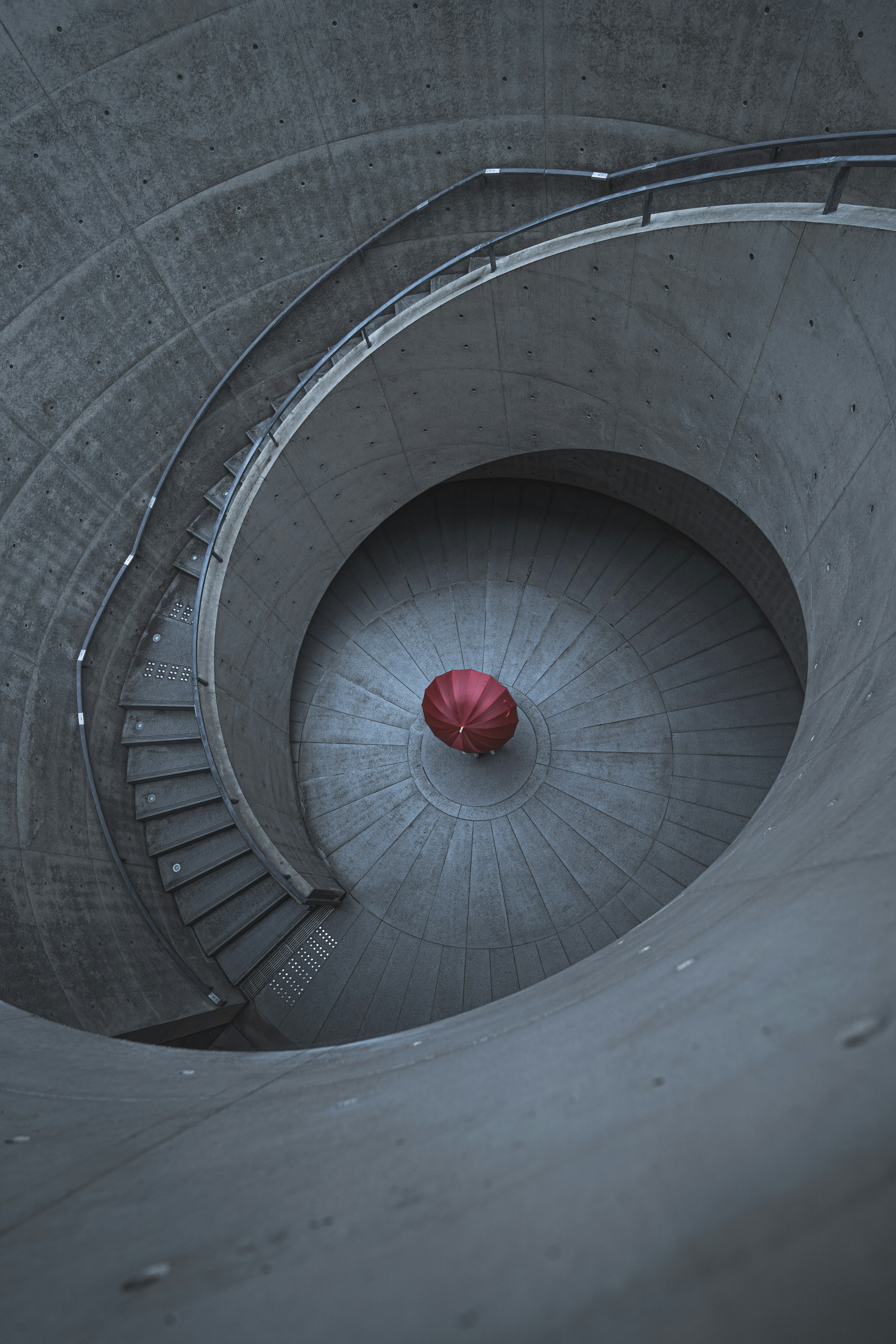 Scala a chiocciola in cemento con una sfera rossa al centro