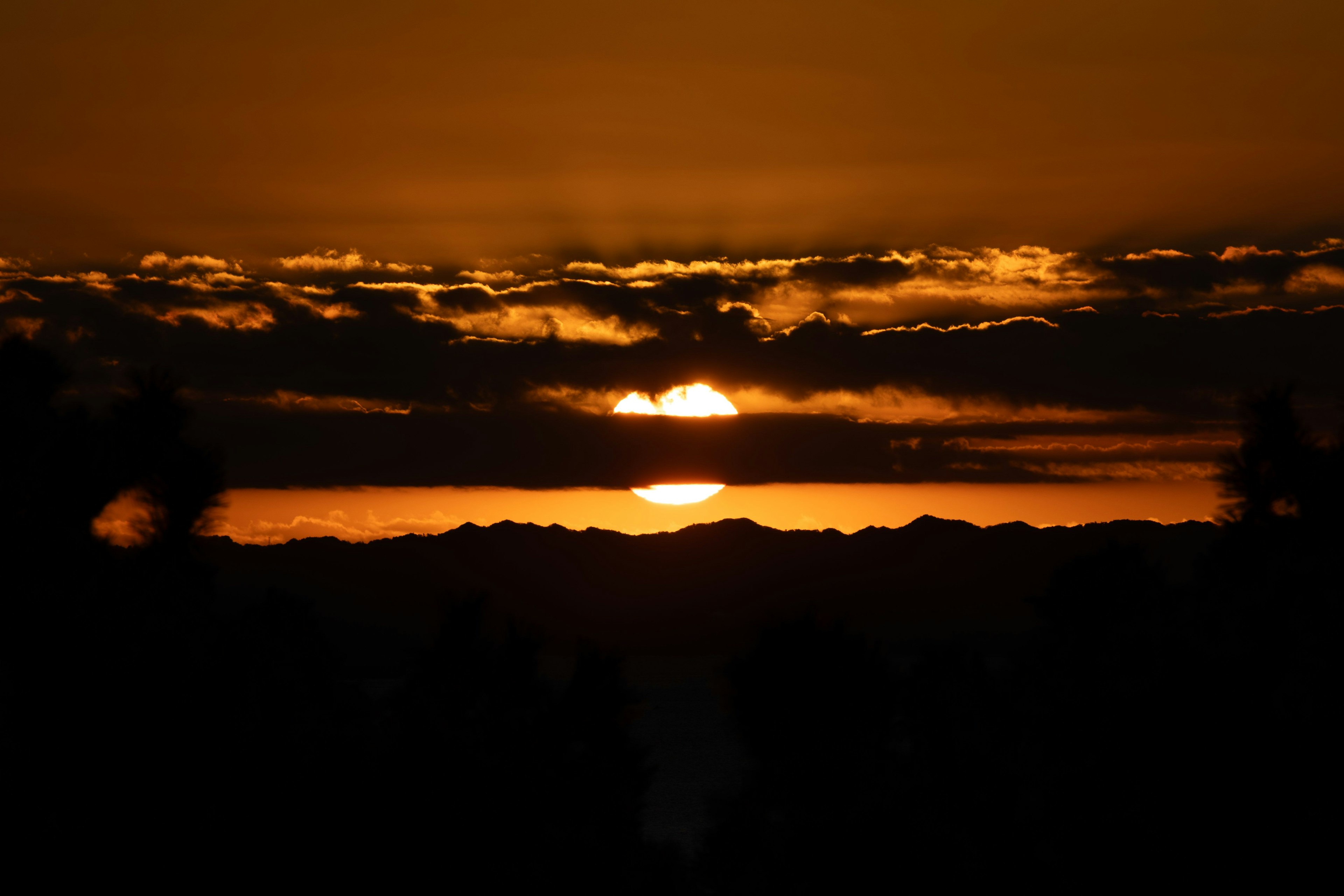夕日が山の上に沈む美しい風景オレンジ色の空と雲が広がる
