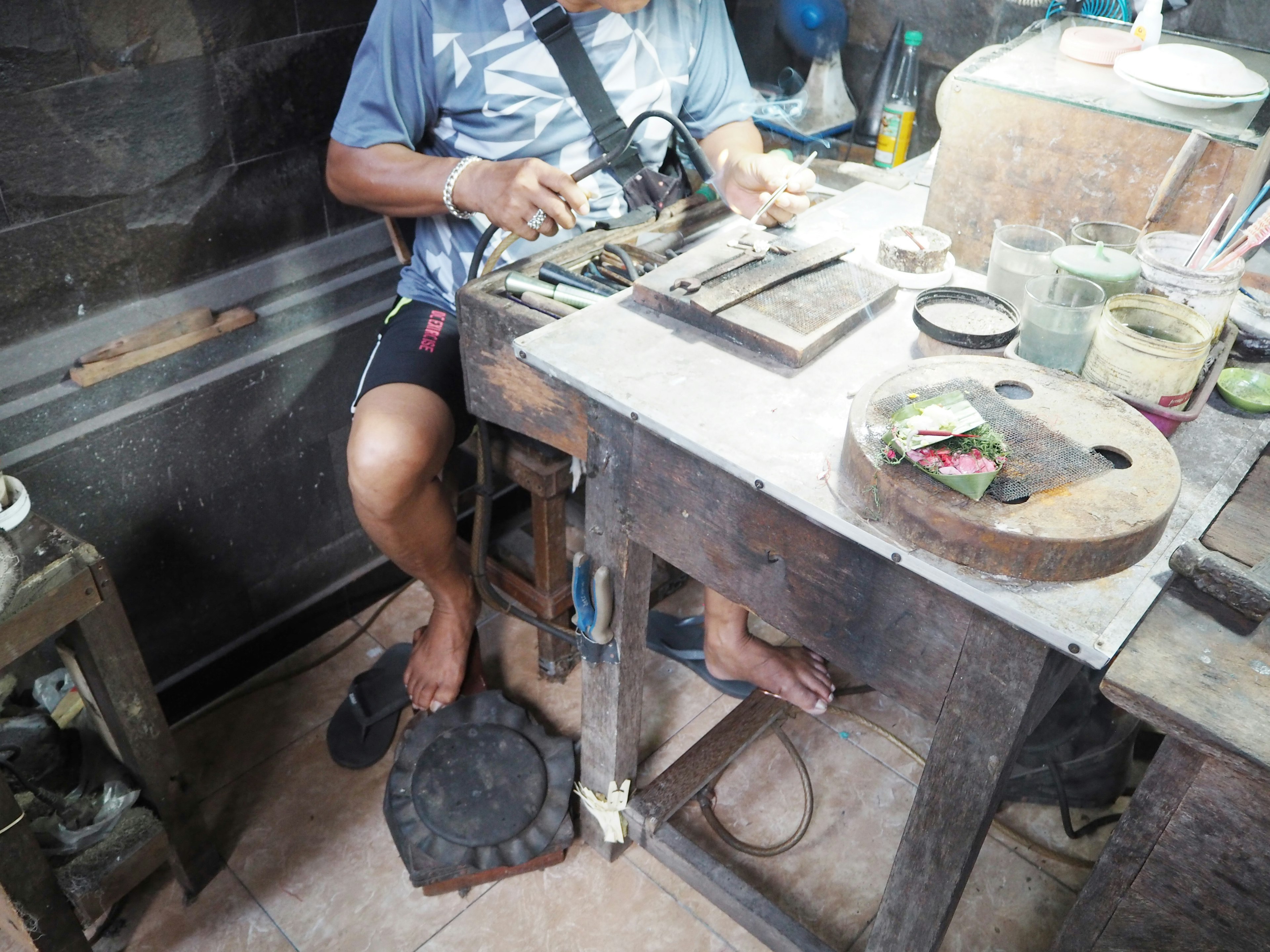 Artisan travaillant à une table d'atelier avec des outils éclairage naturel montrant un espace de travail simple