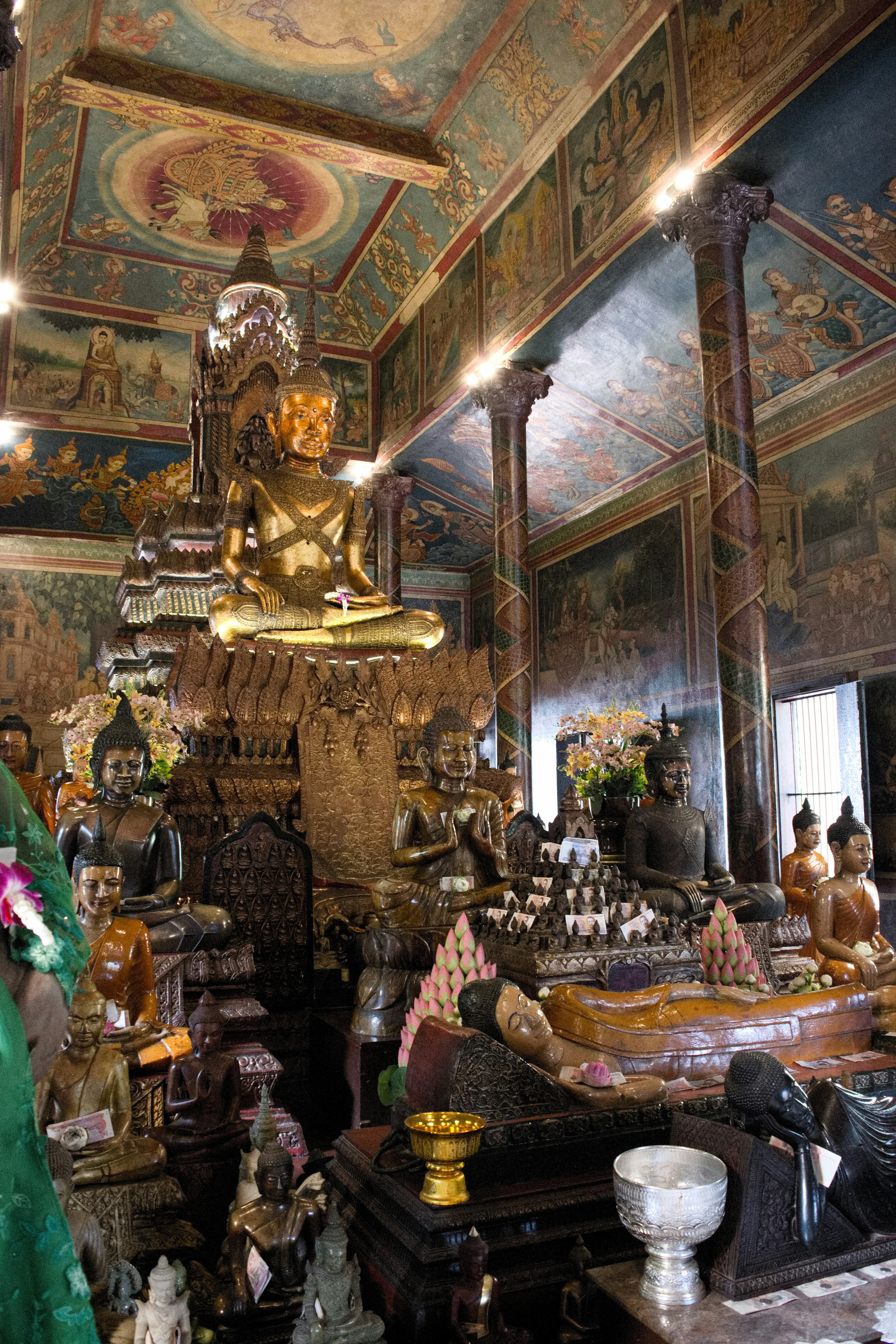 Interior of a temple featuring Buddha statues and decorative ceiling paintings