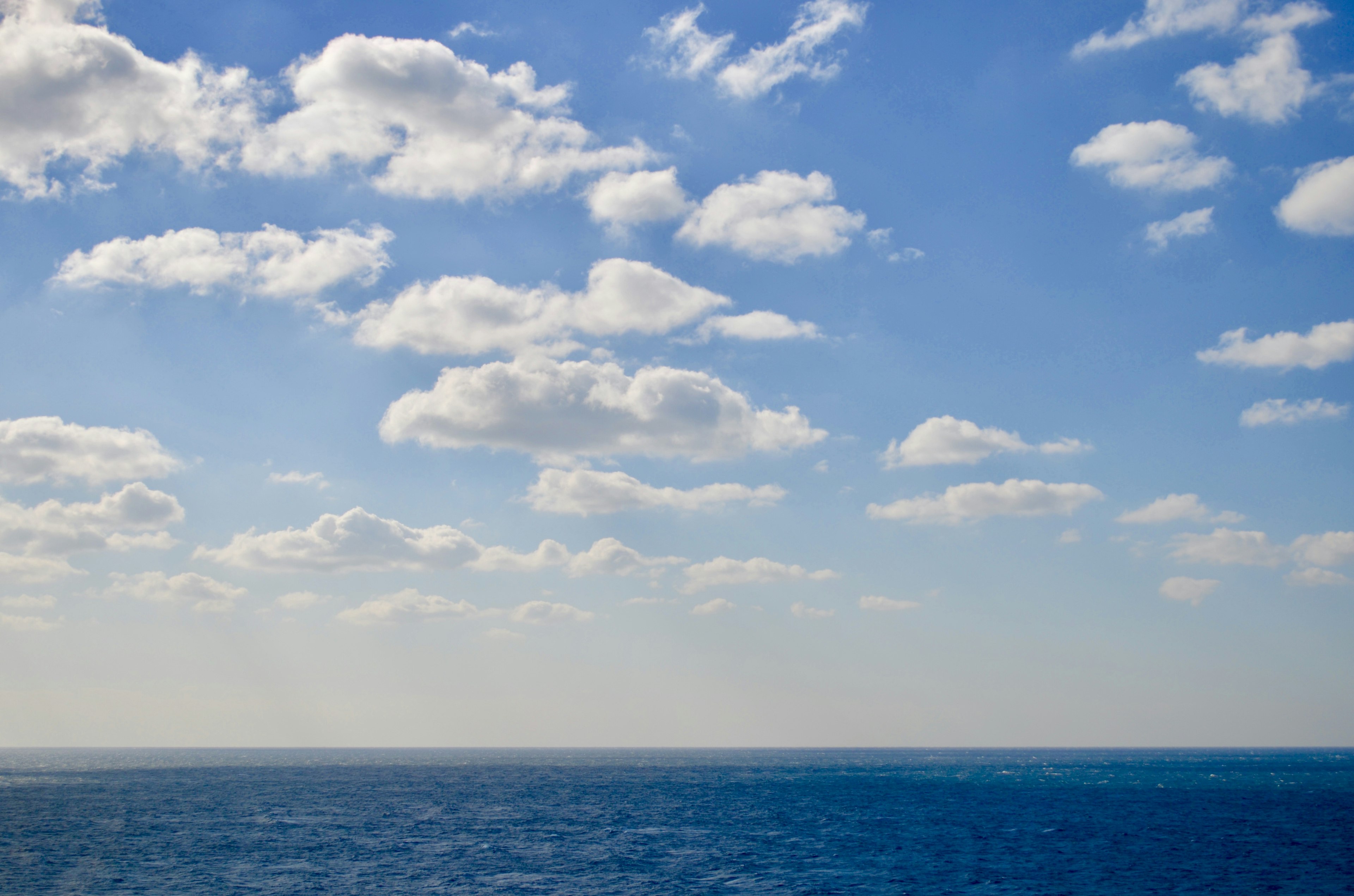 Vaste océan bleu sous un ciel rempli de nuages blancs duveteux