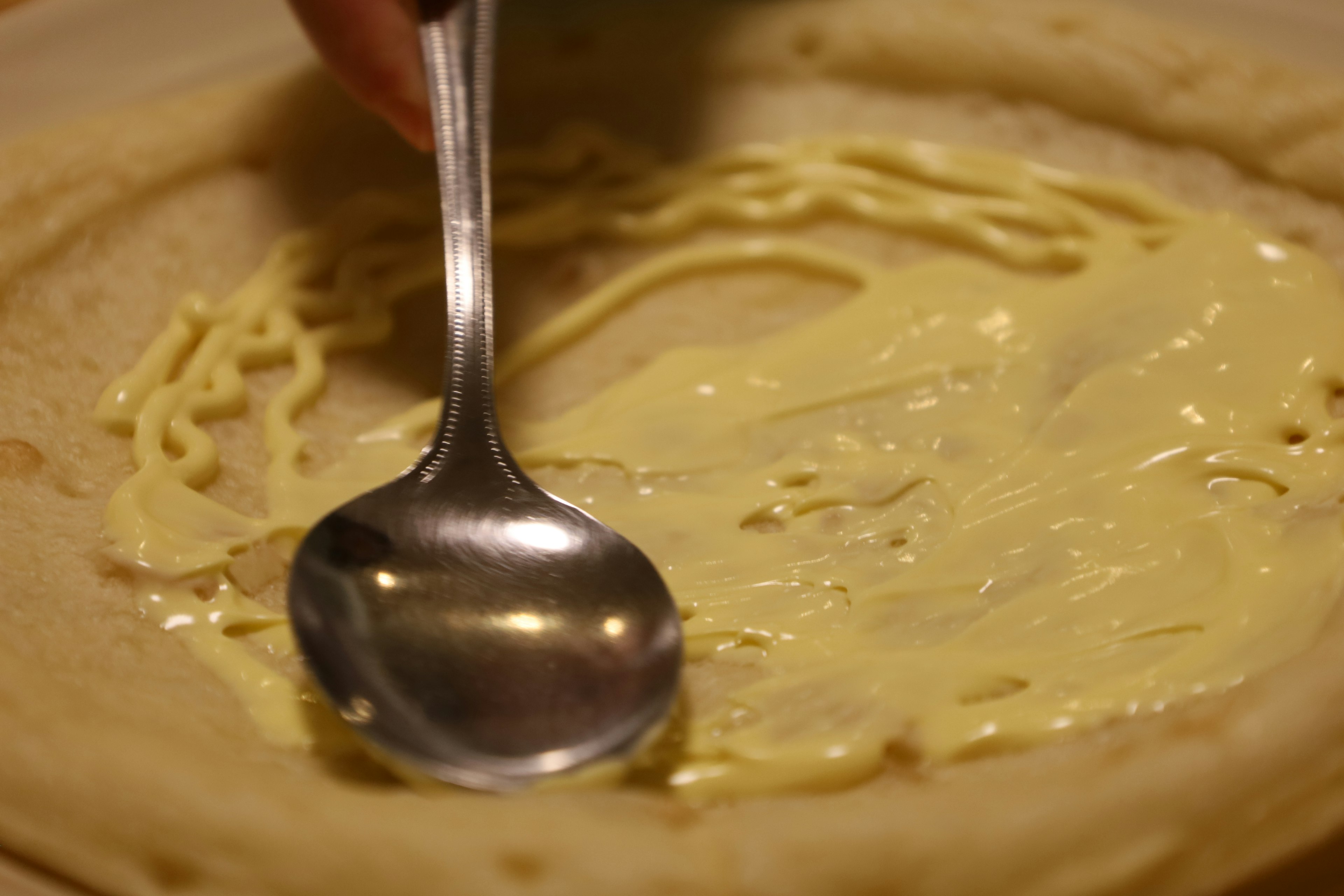 Spreading cream on a pancake with a spoon