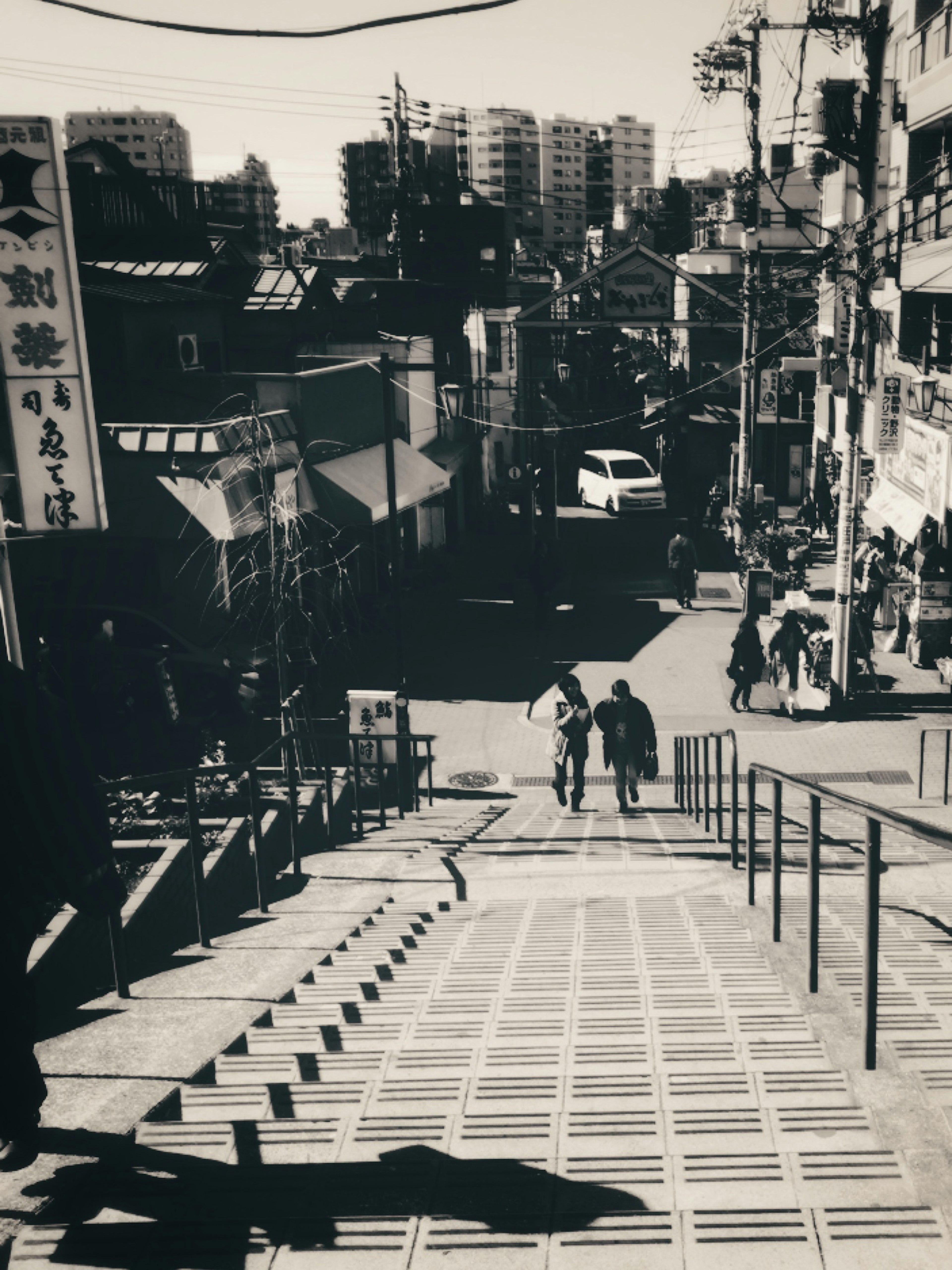 Escena urbana en blanco y negro con personas bajando escaleras y edificios al fondo