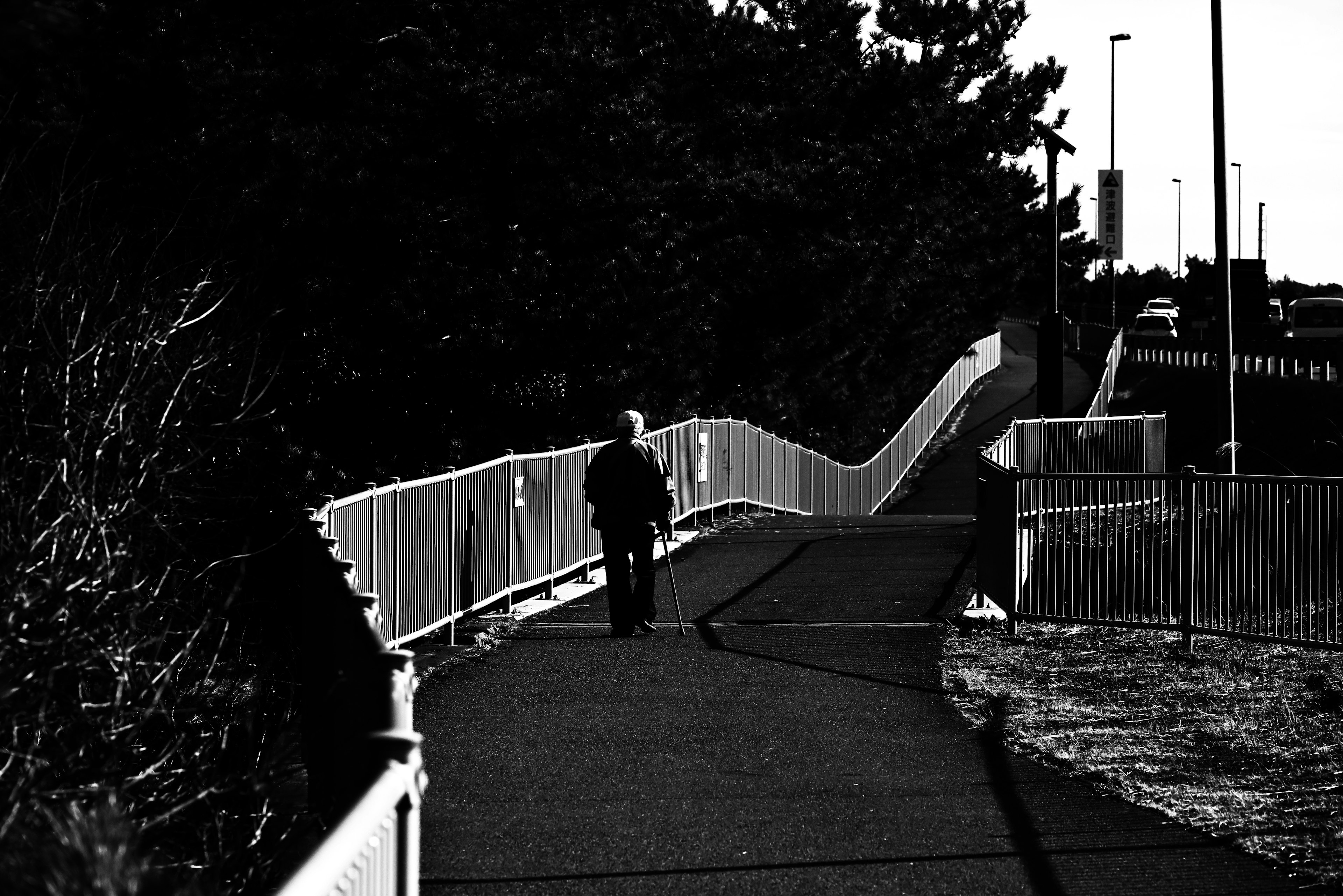 A person walking on a pathway with a white fence