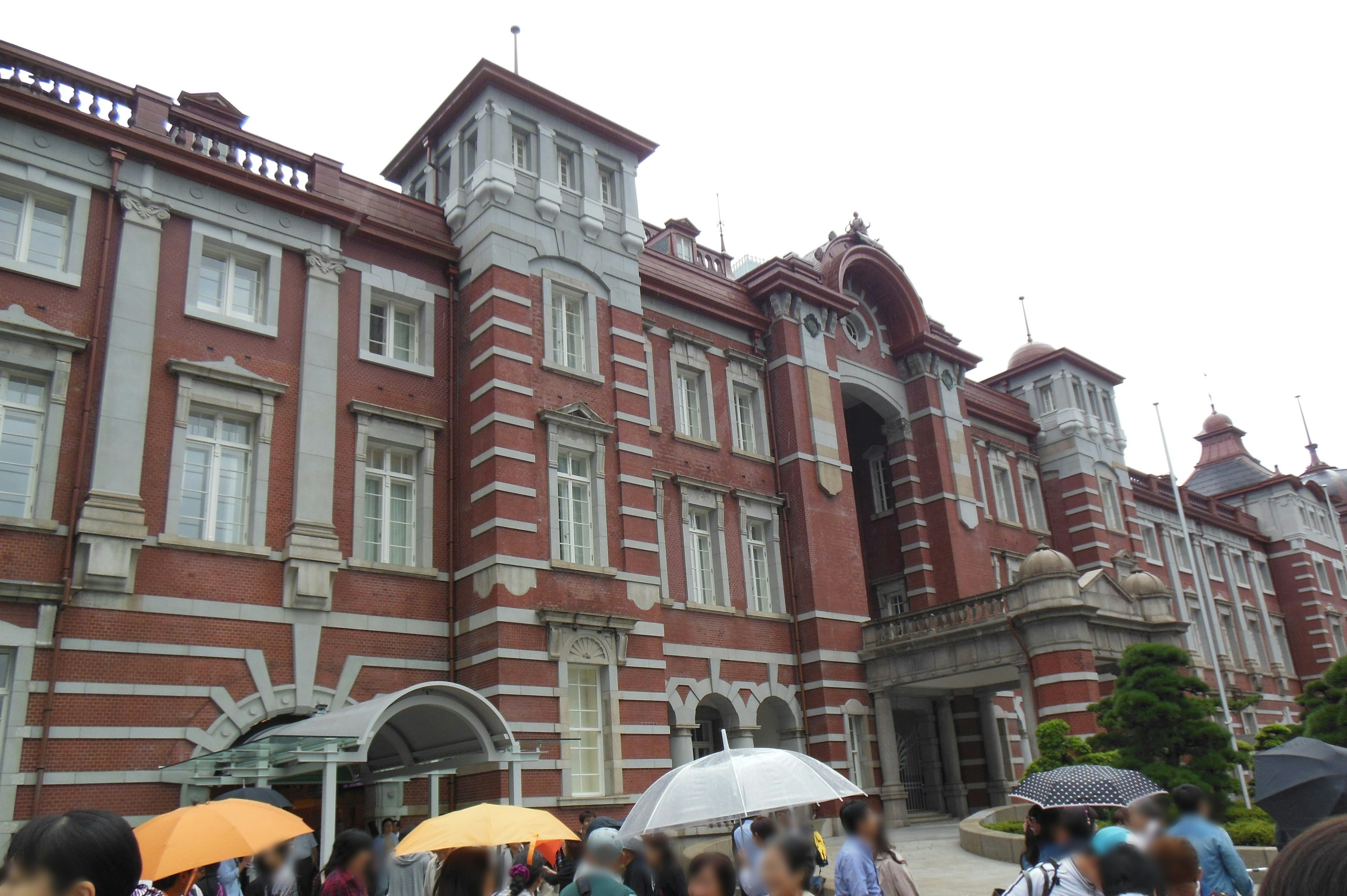 Red brick building with tourists holding umbrellas