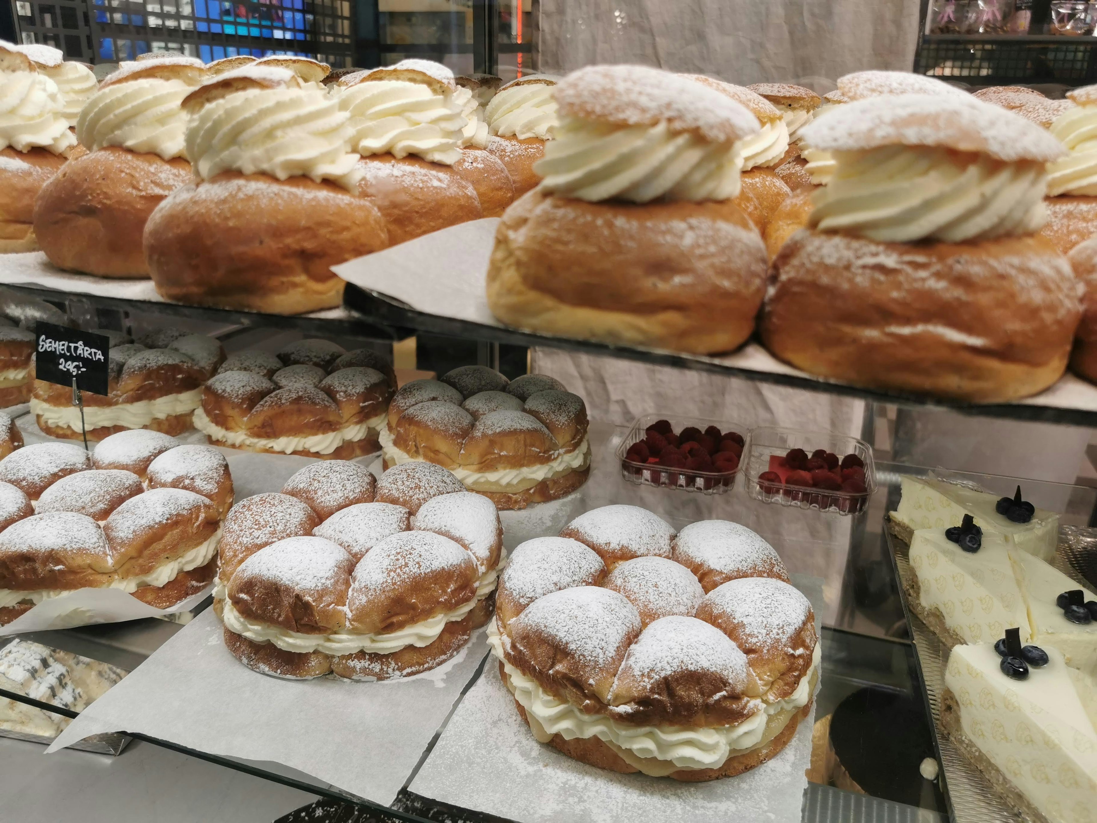 Large cream-topped donuts and cream-filled small cakes arranged on display