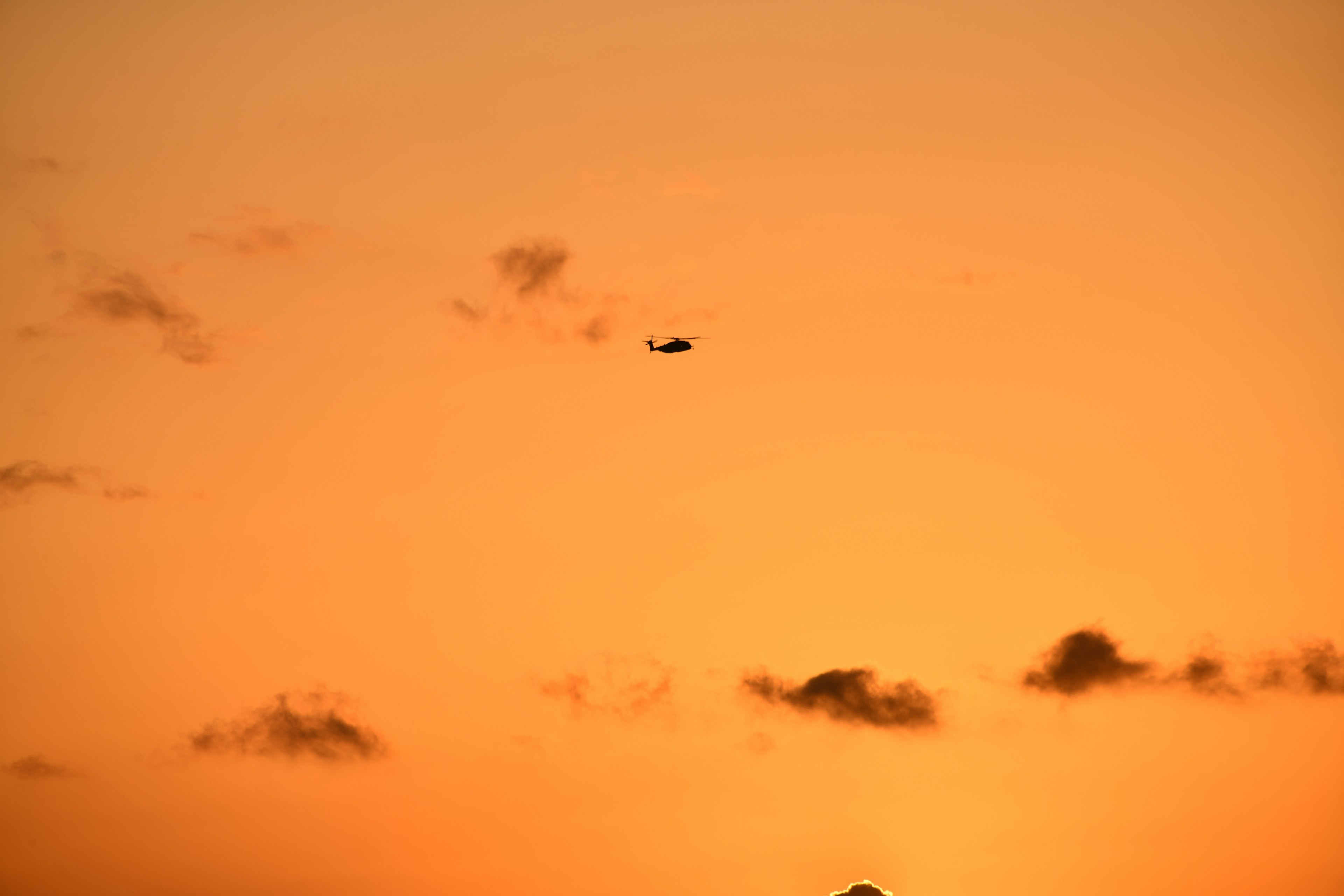 Helicopter silhouette against a sunset sky with clouds