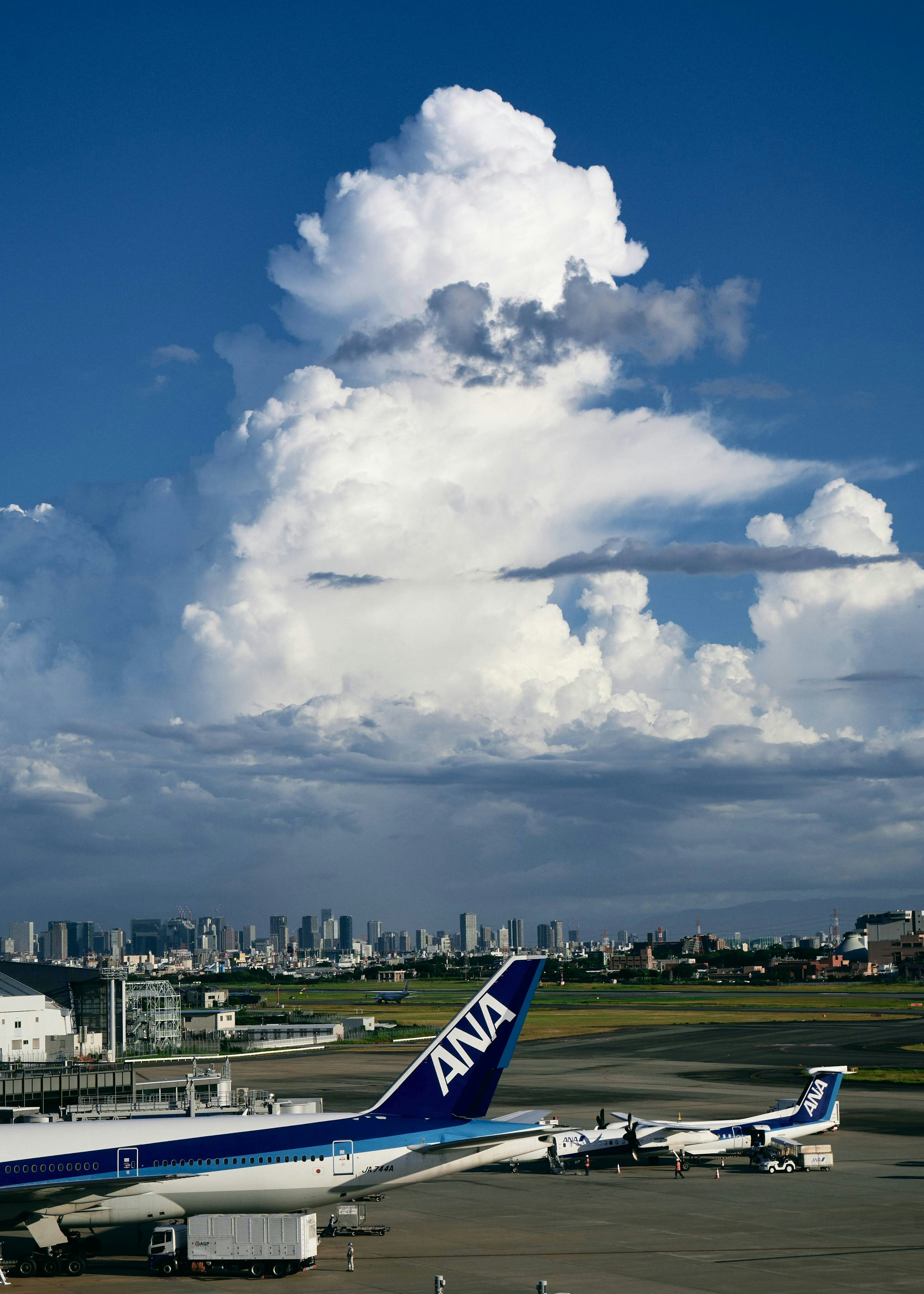 Vista de un avión de ANA en el aeropuerto con grandes nubes en el cielo