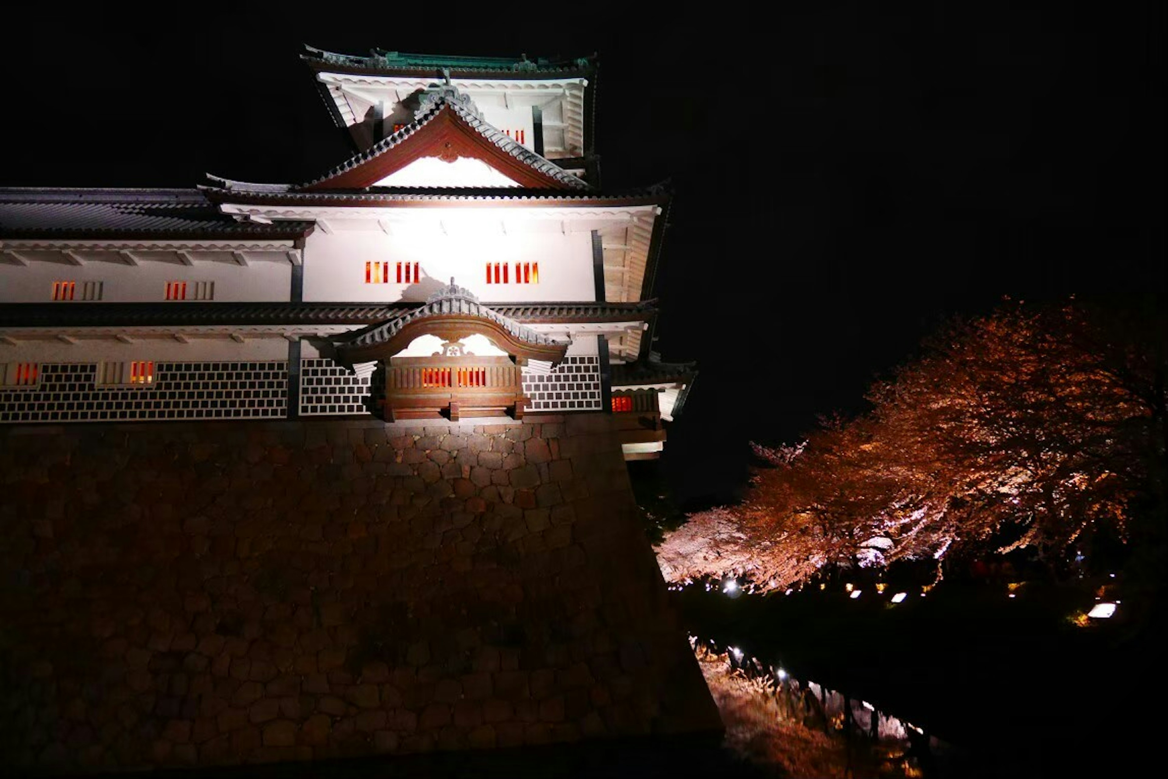 Beleuchtetes Schloss bei Nacht mit Herbstlaub