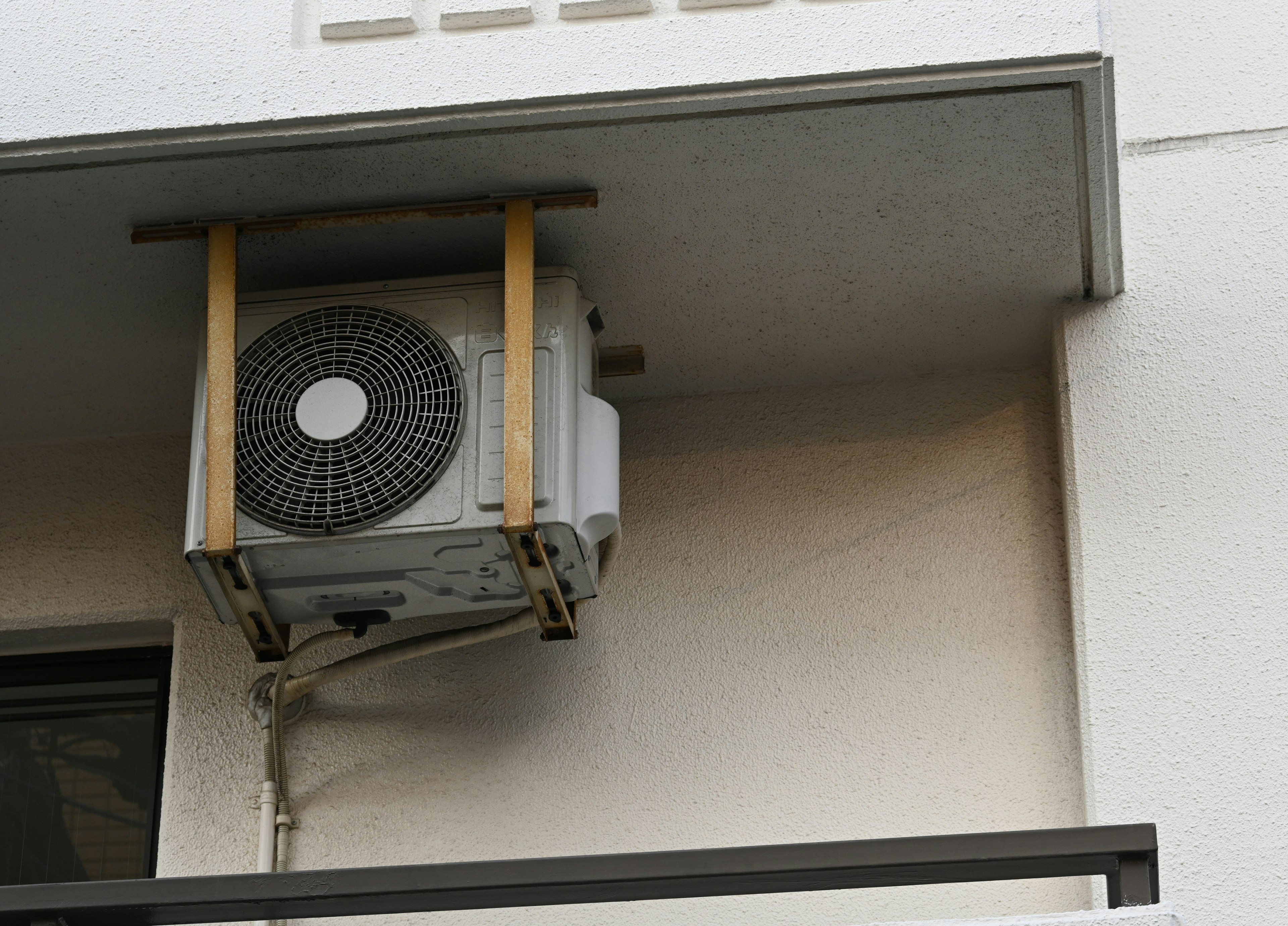 Air conditioning unit mounted on an exterior wall with visible wooden support frame