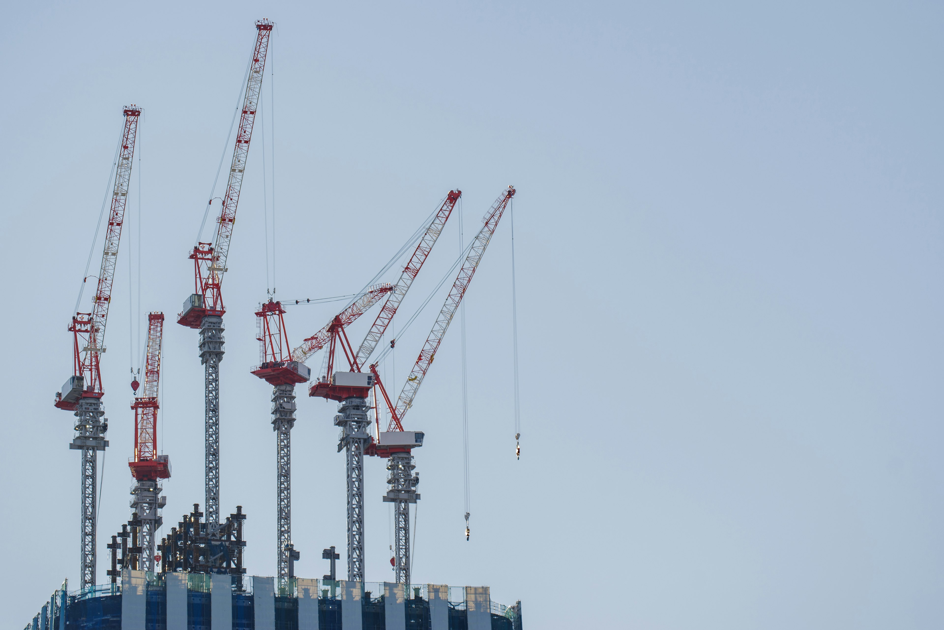 Red and white cranes on top of a skyscraper